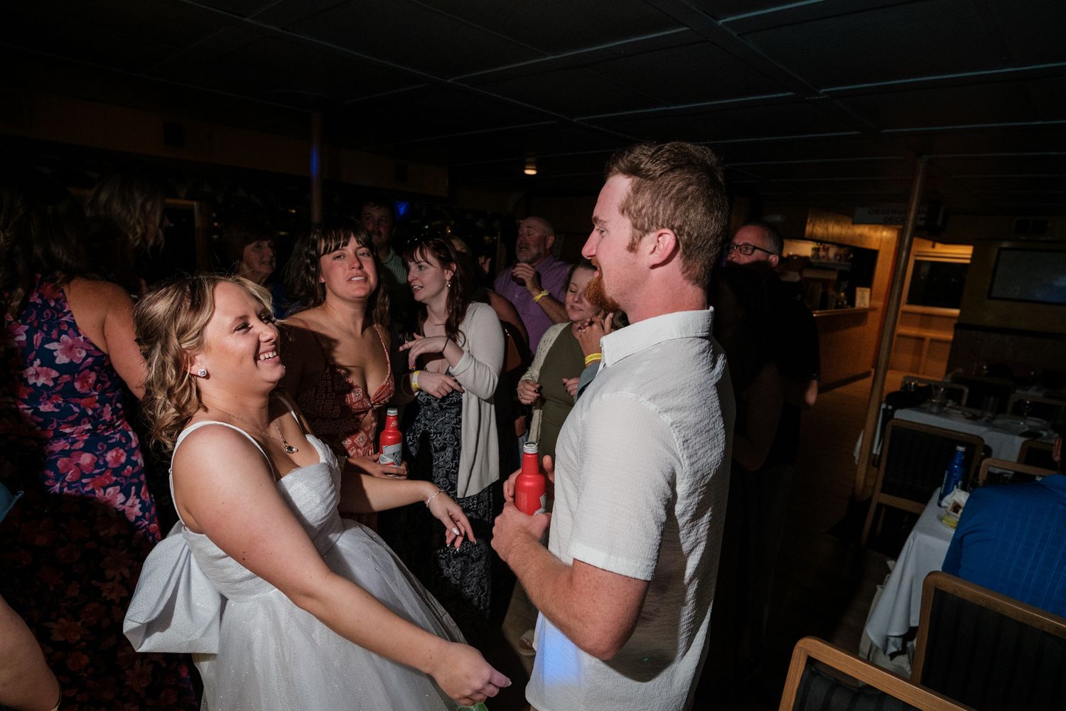 Wedding guests enjoying themselves on a dance floor during an evening reception celebration.