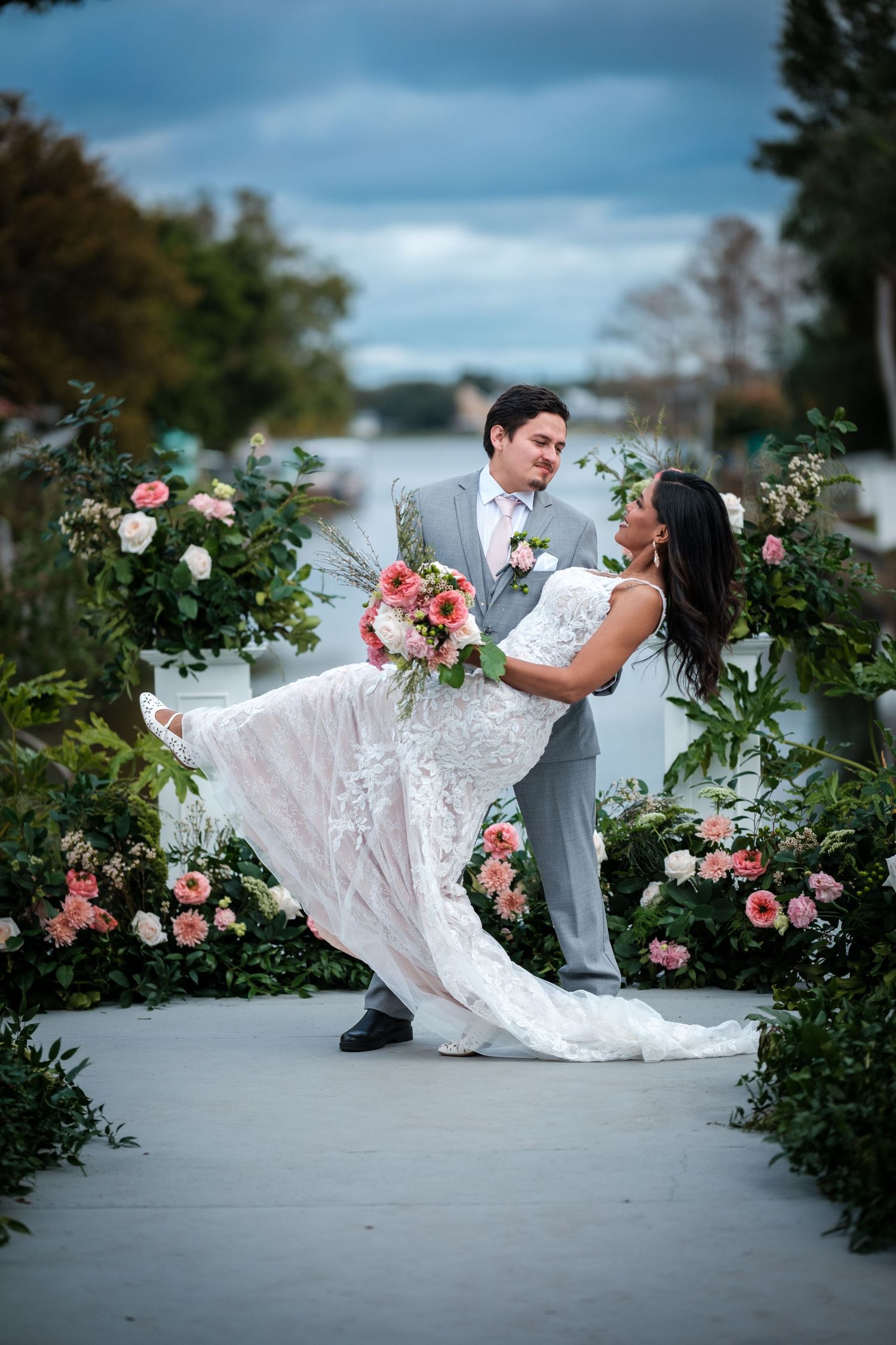 Creative wedding photography with dramatic dip poses among blooming rose bushes.