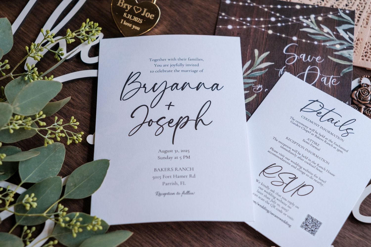 Wedding invitation suite featuring elegant calligraphy and greenery details laid out on a white surface.