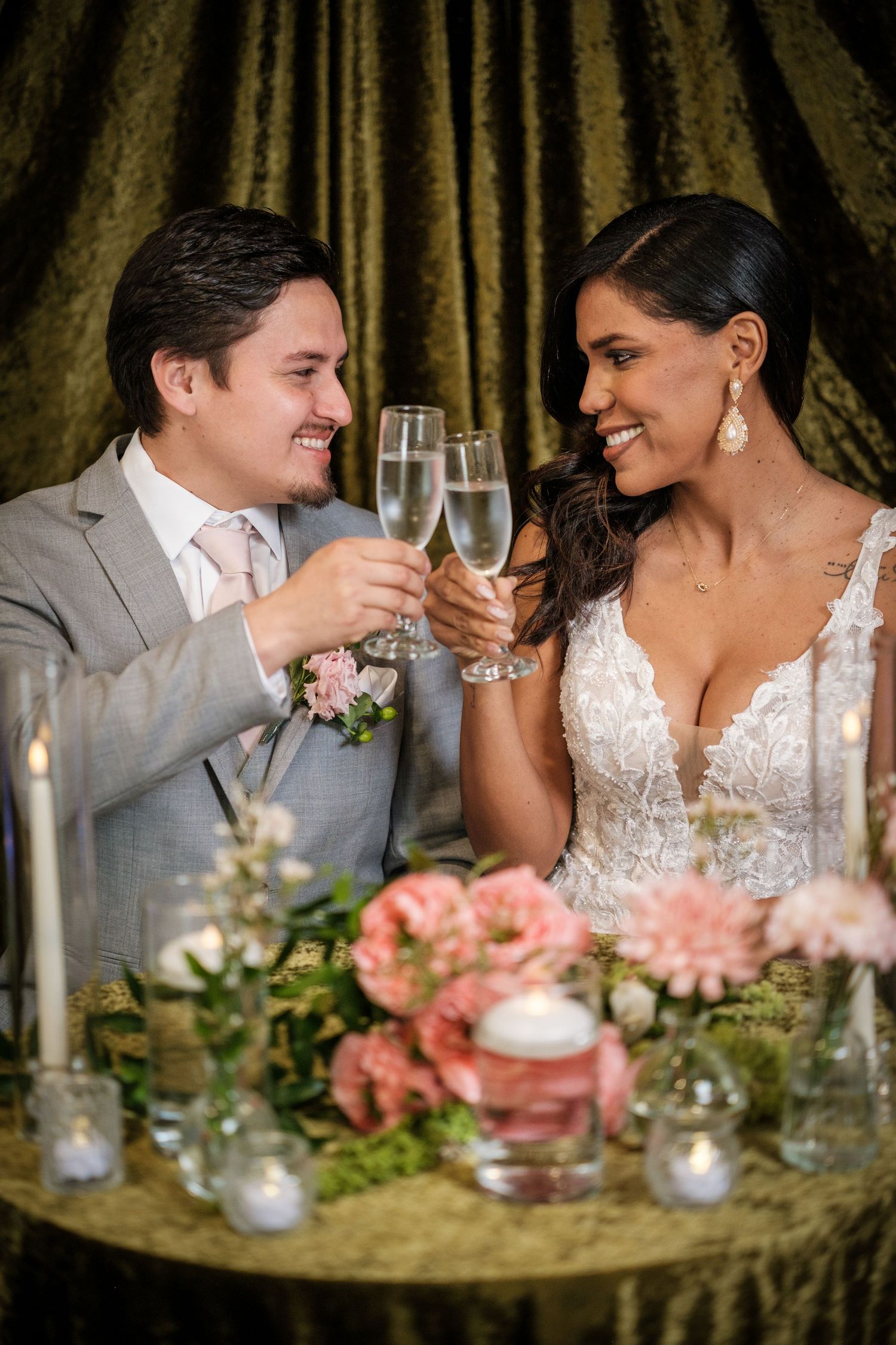 A couple shares intimate moments at their wedding reception table decorated with pink flowers and candles.
