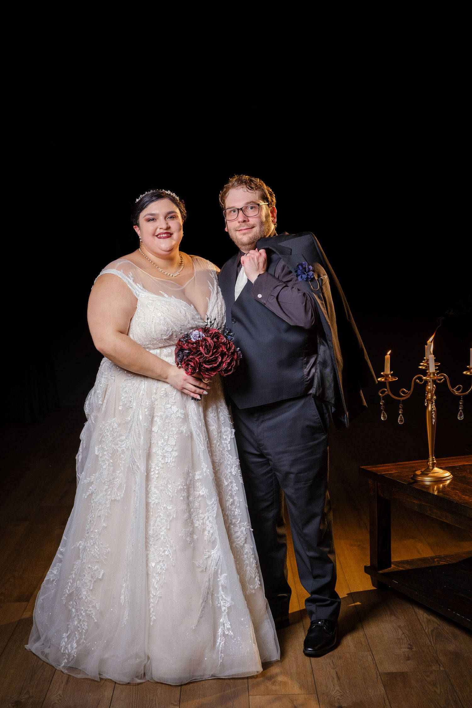 A couple poses together during their wedding celebration in a dimly lit venue with elegant candelabras in the background.