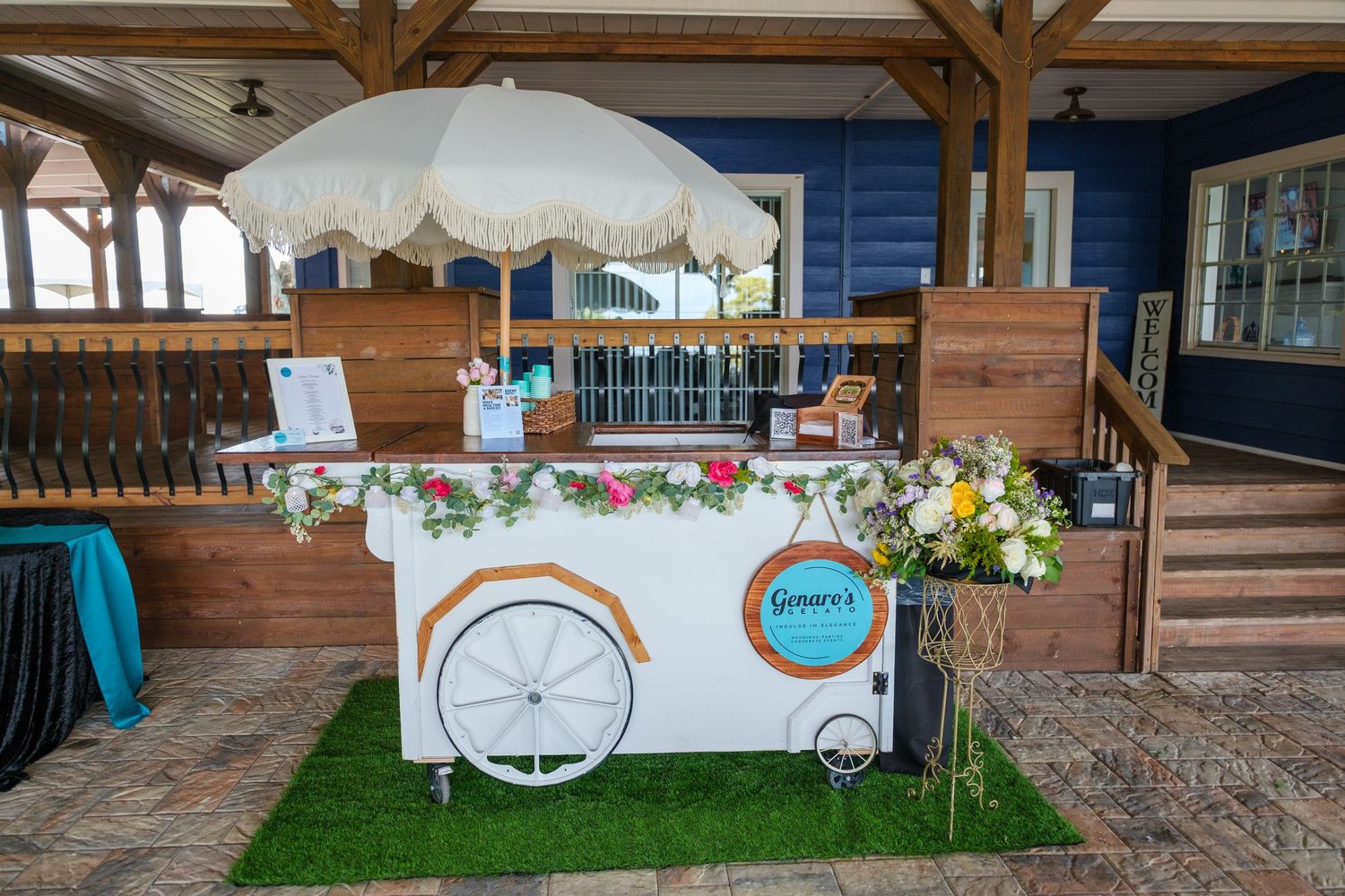 Rustic outdoor patio with wooden beams and vintage decor features a white wagon wheel mounted on blue siding.
