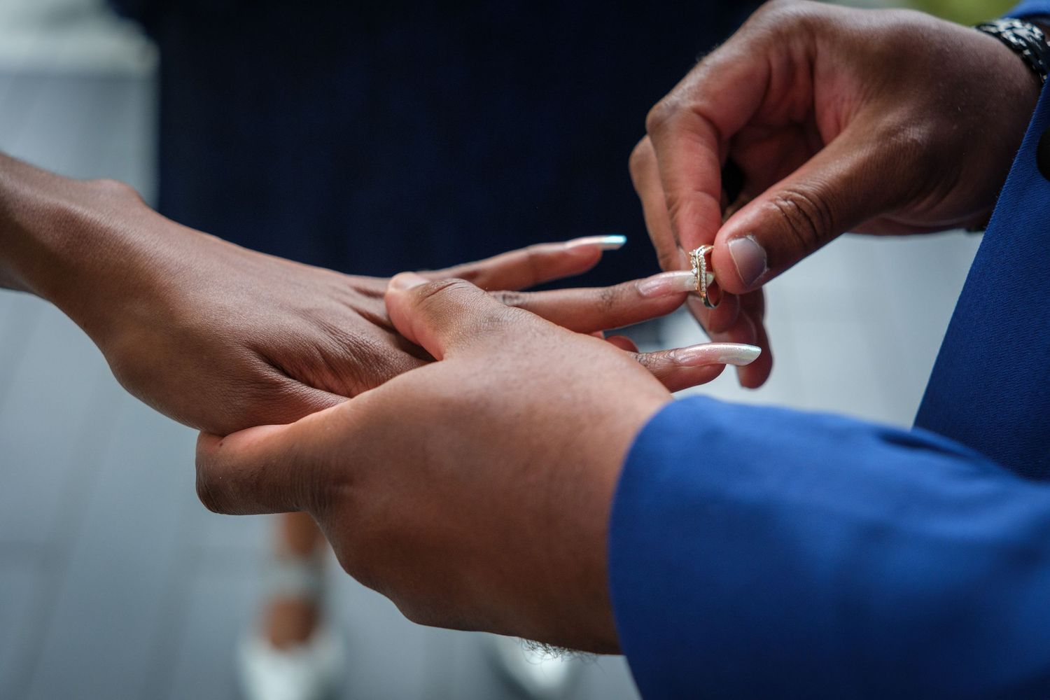 Close-up of a wedding ring exchange ceremony, with hands placing a gold band on a finger.