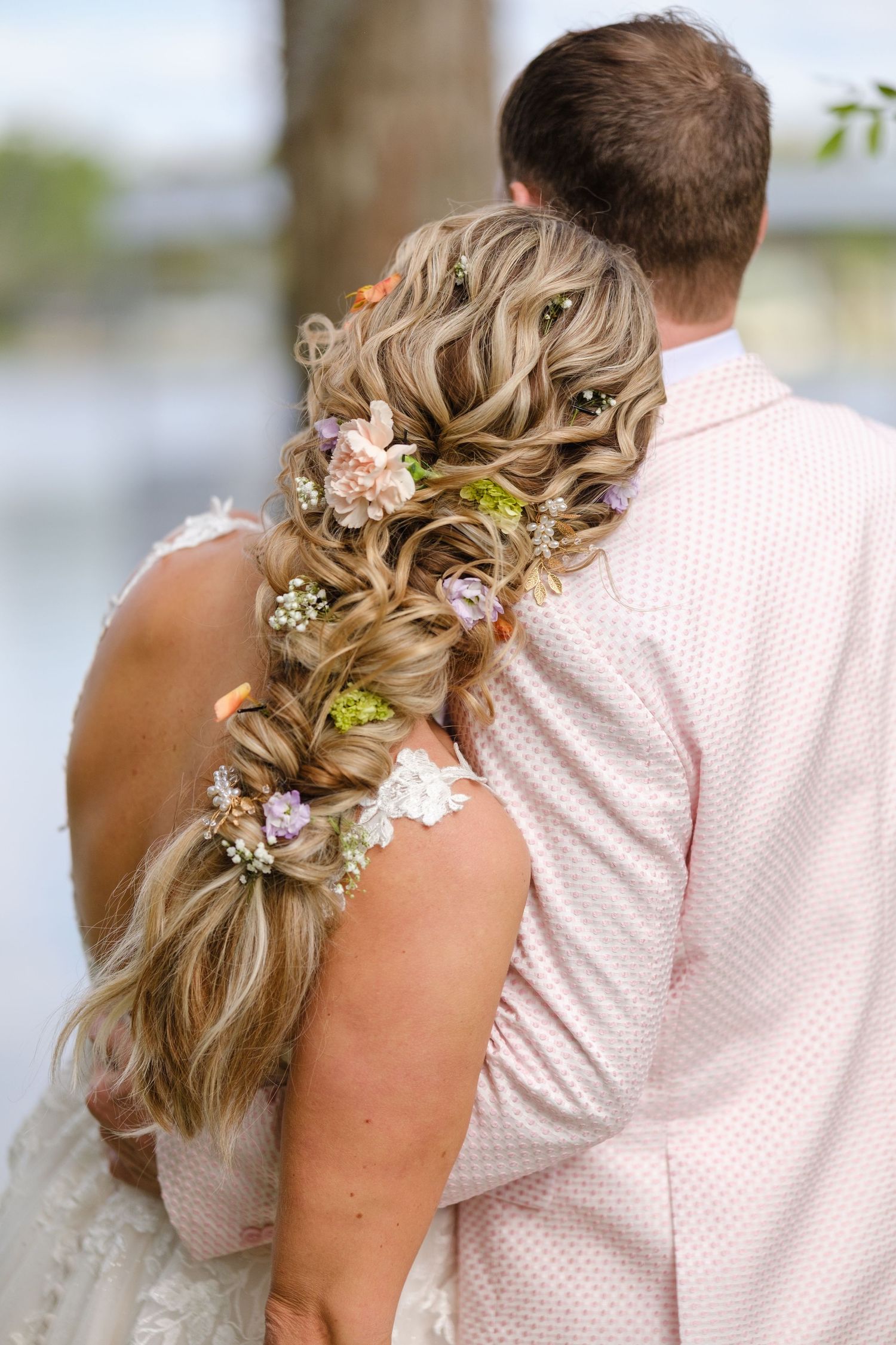 A romantic wedding hairstyle featuring soft waves adorned with delicate baby's breath flowers and greenery.