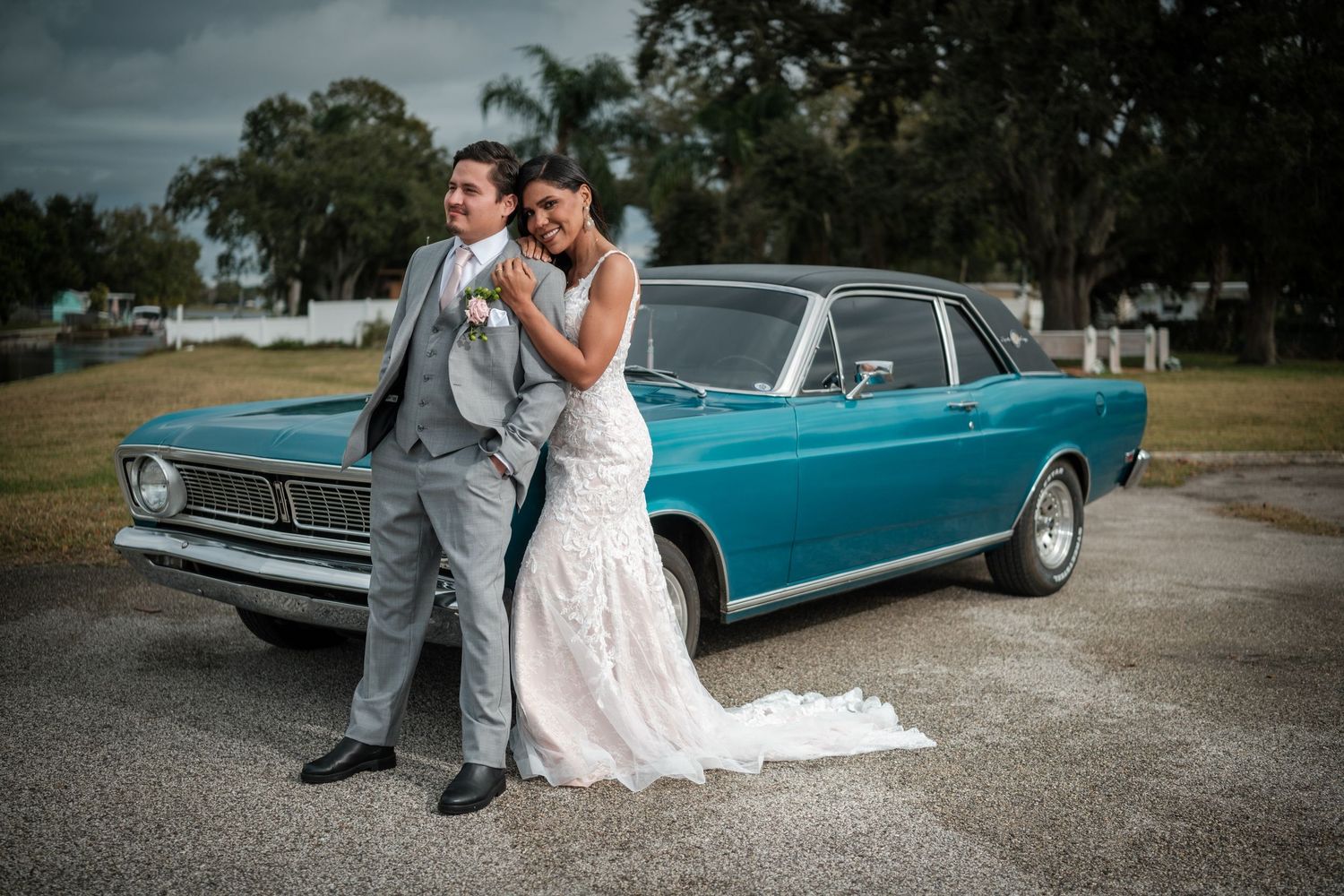 Artistic wedding photography featuring a couple and vintage turquoise car on a gravel lot.