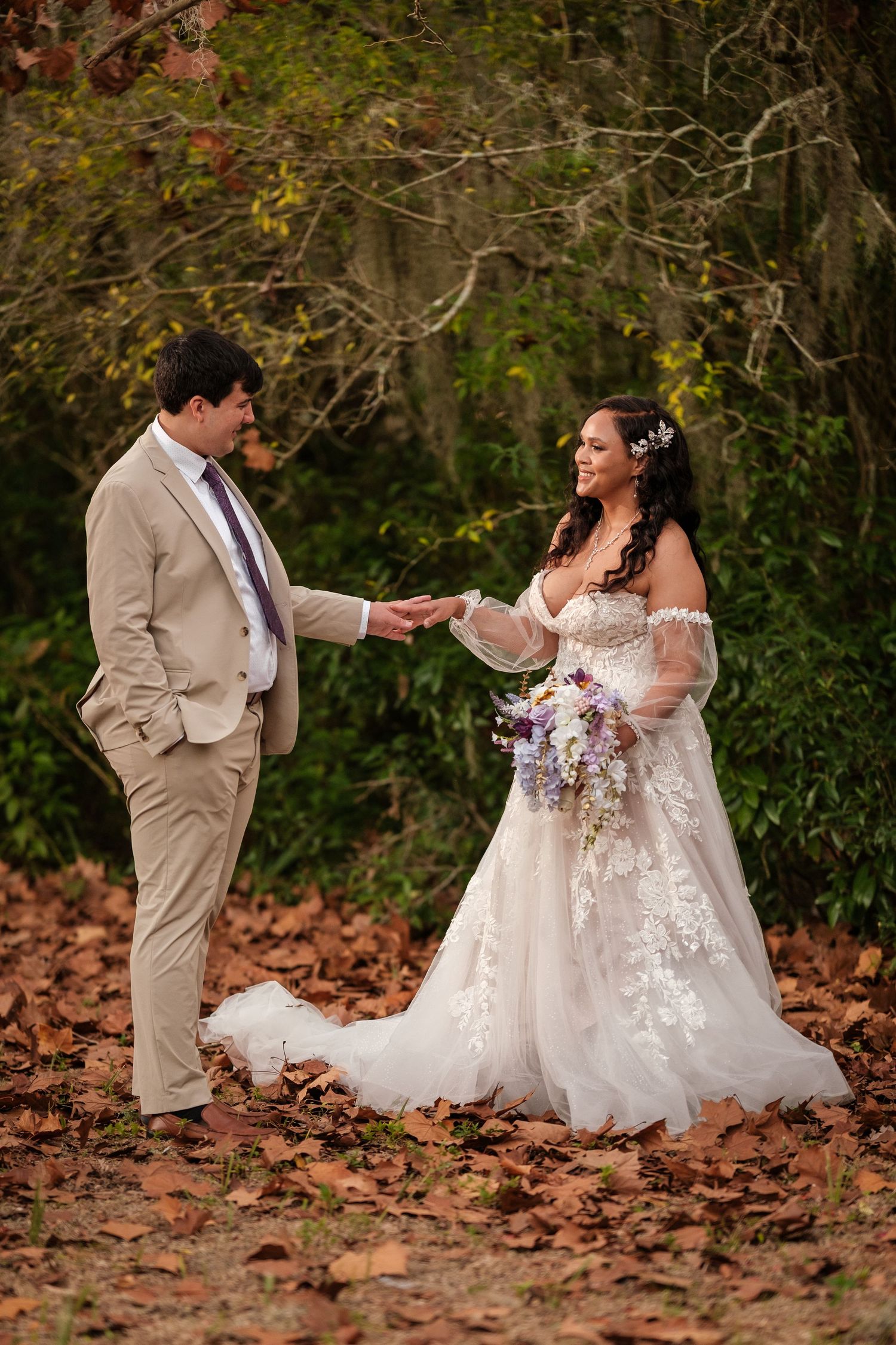 A couple in wedding attire dances together on autumn leaves in a romantic outdoor photoshoot sequence.