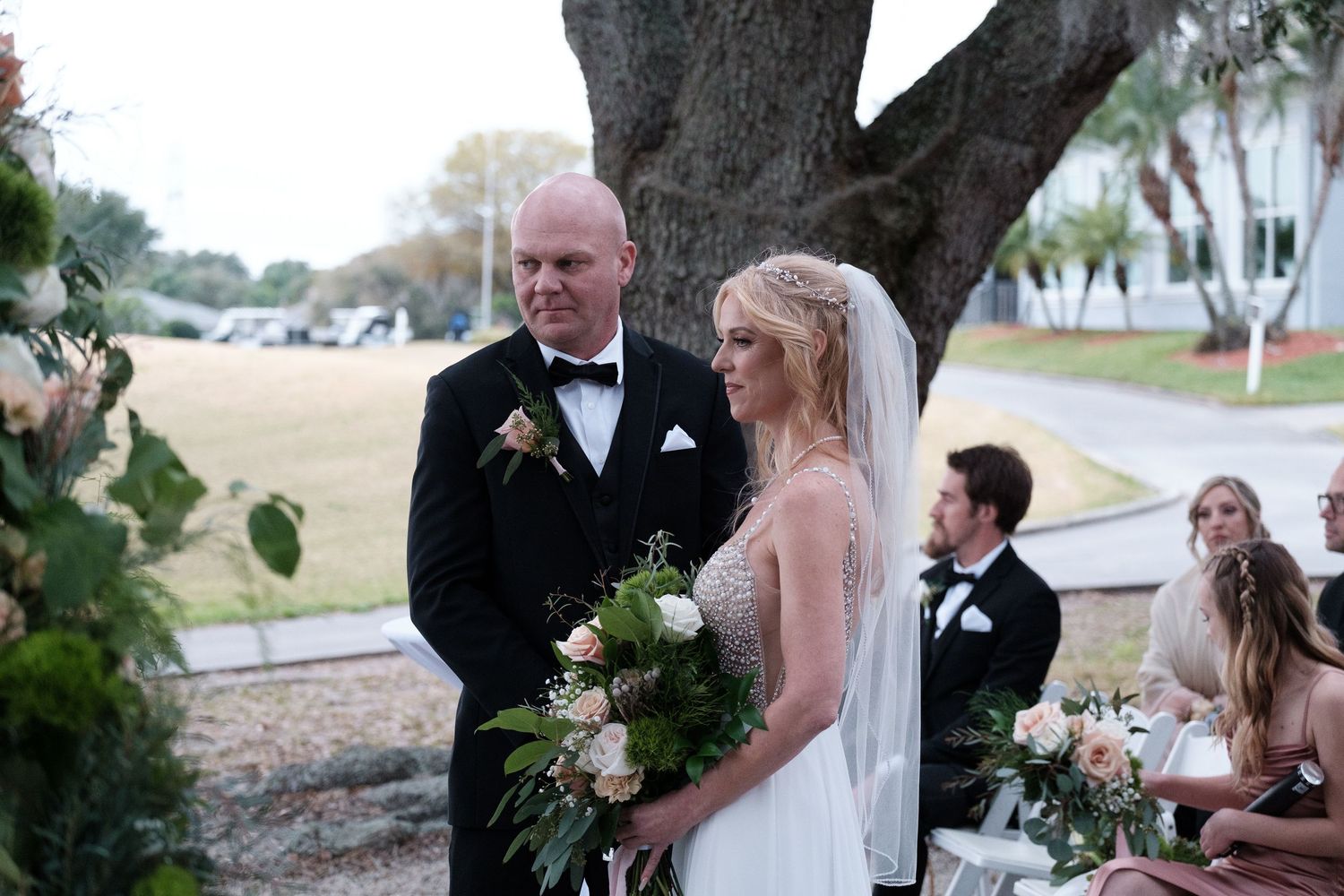 Wedding party gathers outdoors near a waterfront location during a beautiful sunset ceremony.
