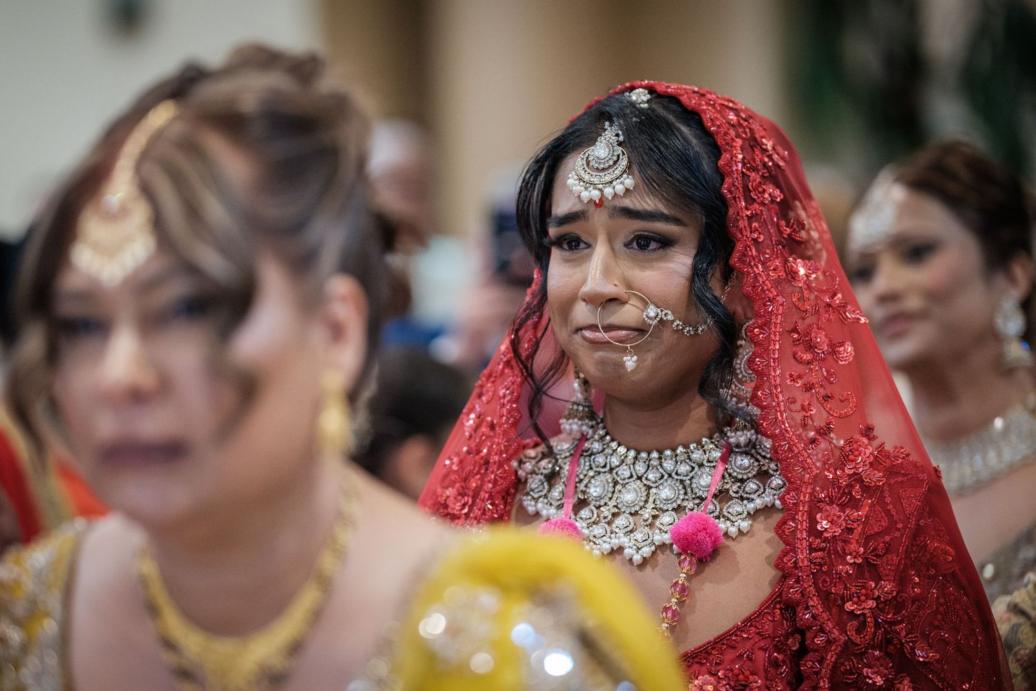 Indian bride in red bridal lehenga and silver jewelry at traditional Hindu wedding ceremony.