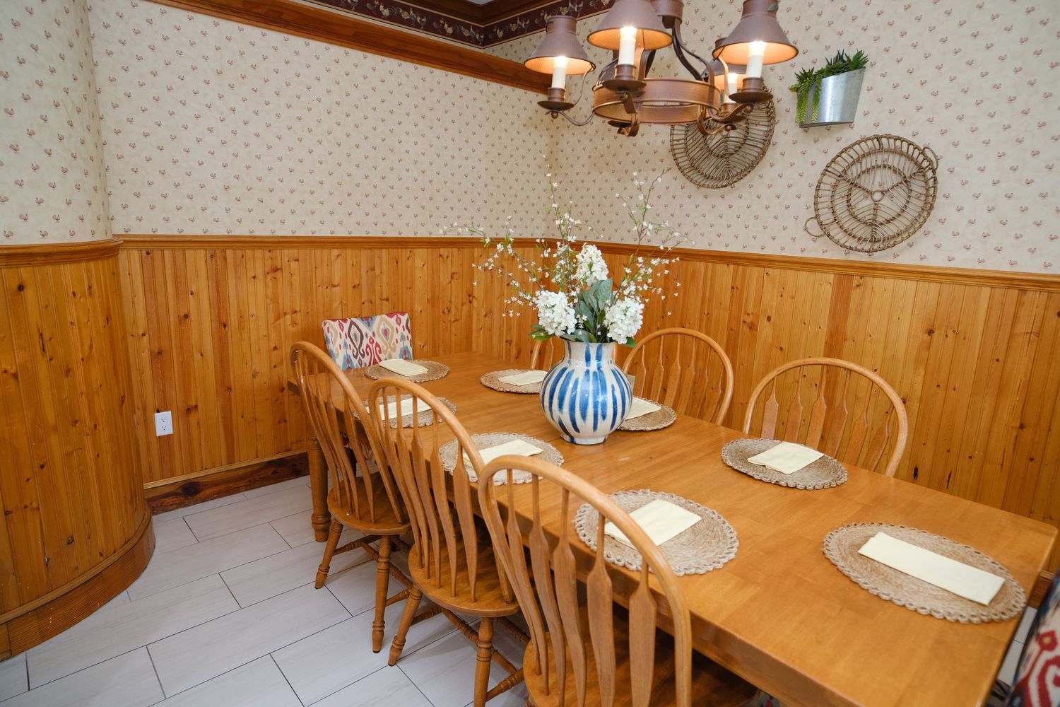 Country-style dining room with wood paneling, long wooden table and yellow floral centerpiece.