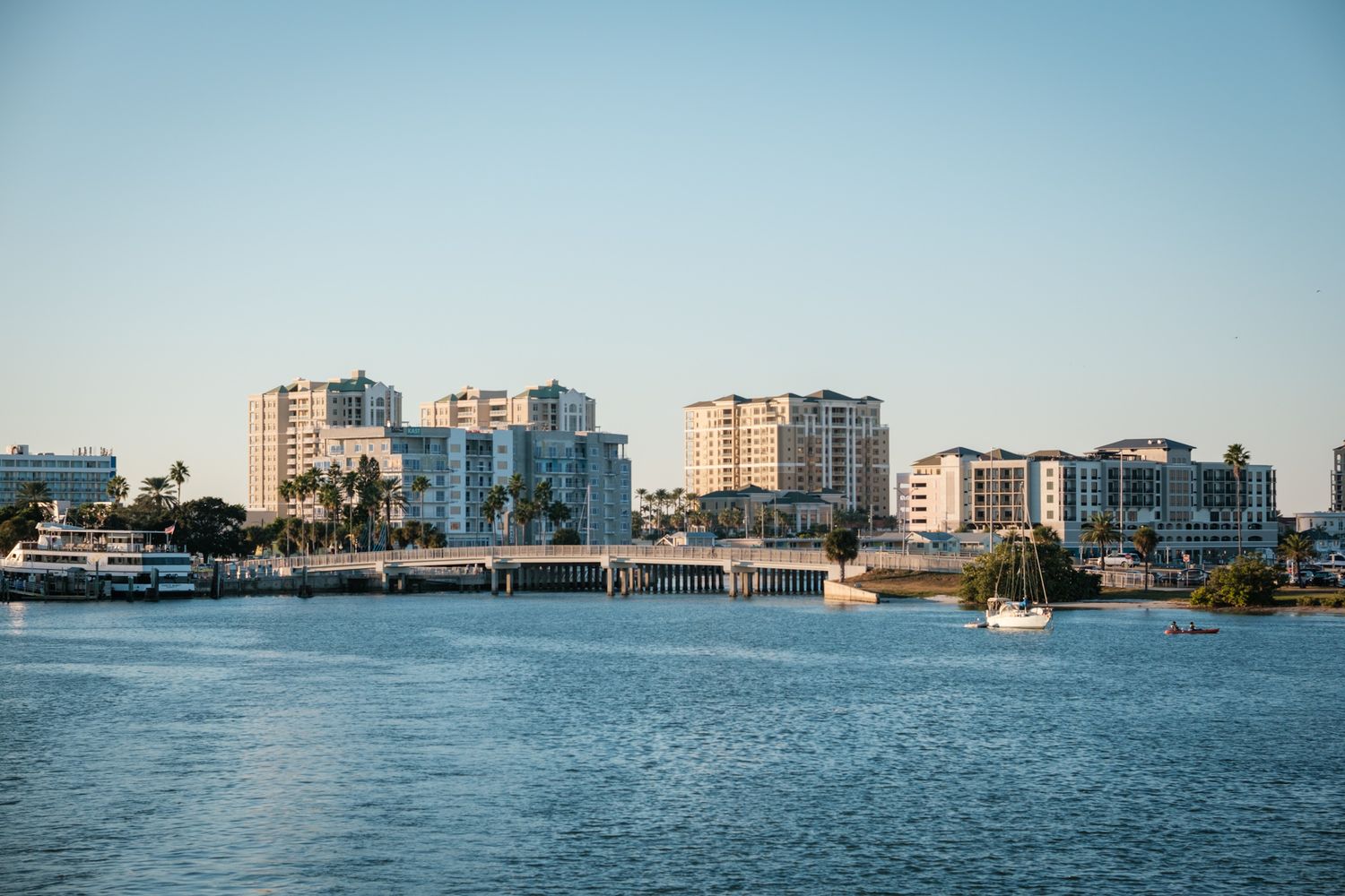Coastal cityscape with waterfront buildings and boats along shoreline.