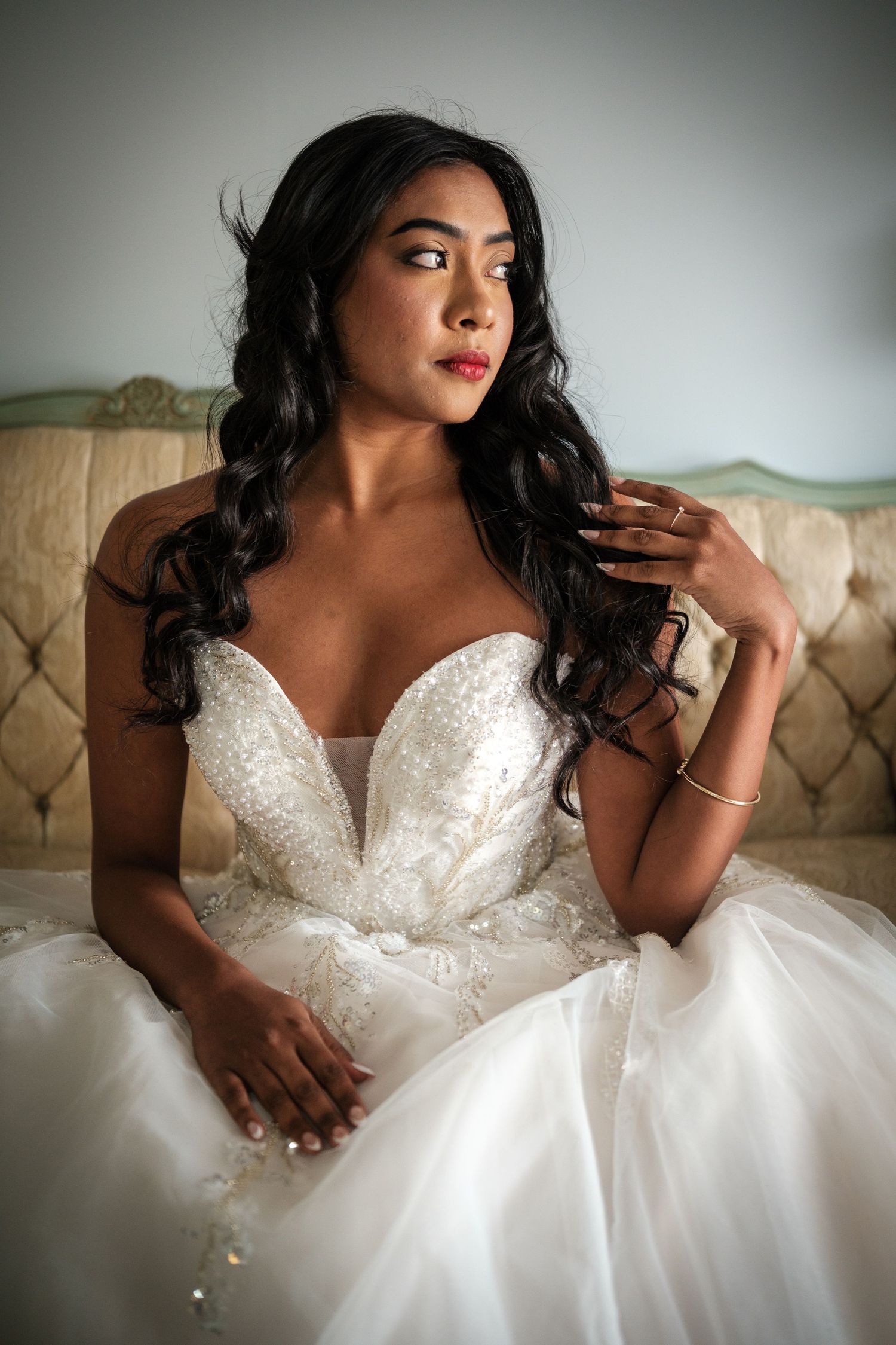Close up of white beaded wedding dress with sweetheart neckline against light background.