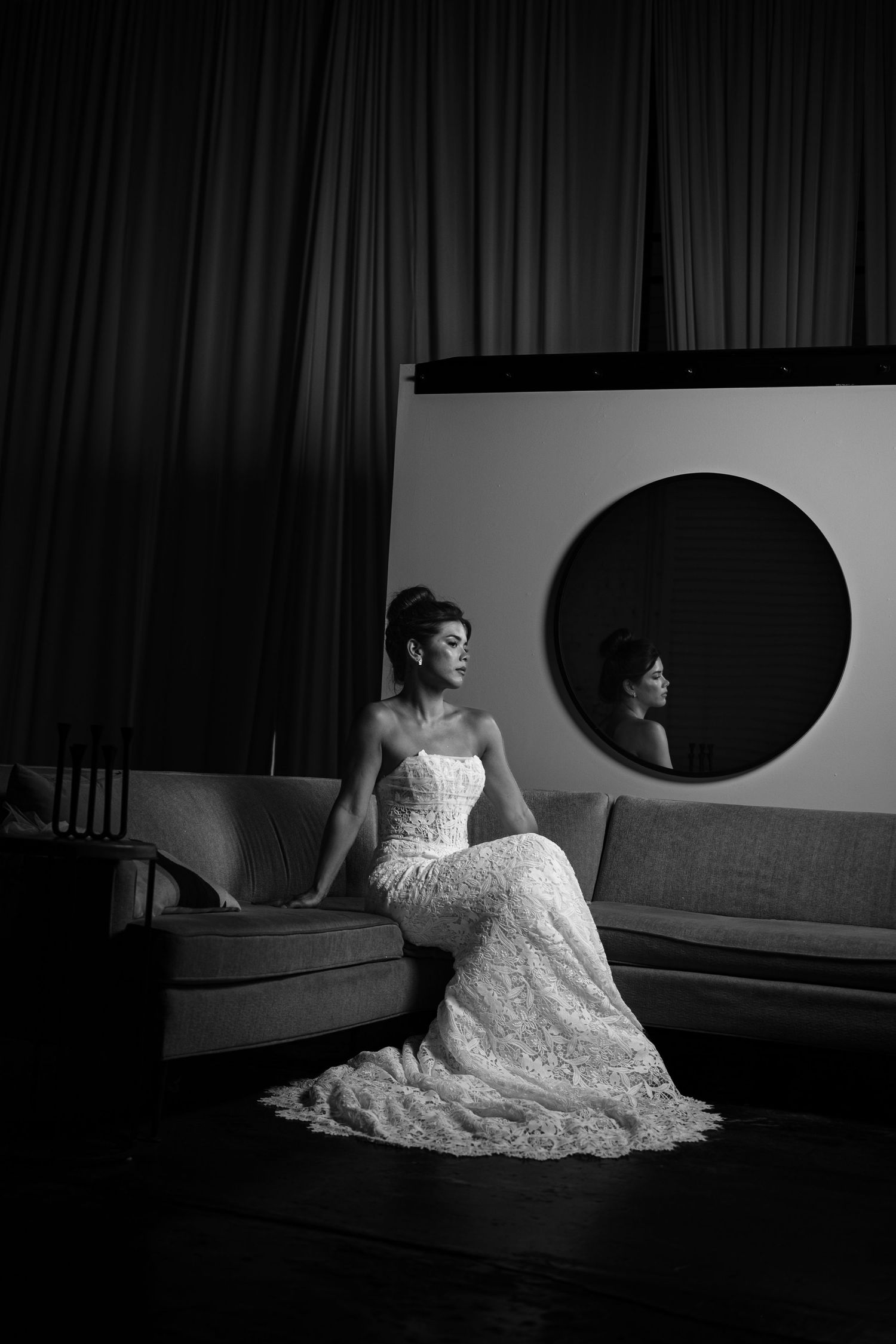 A dramatic black and white bridal portrait series showing a bride in a lace gown seated on the floor in various poses.