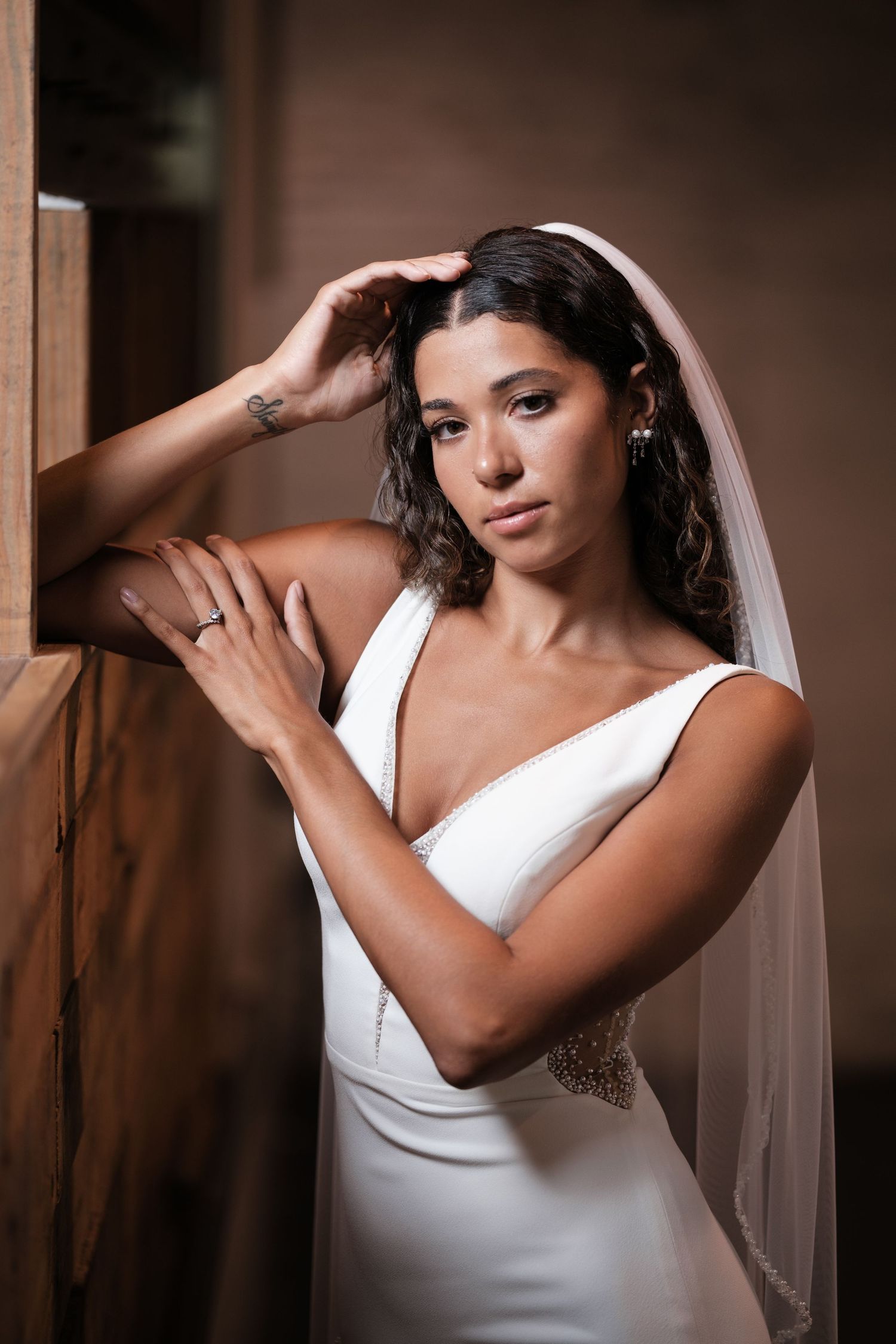 A dramatic bridal portrait series with elegant poses in a white gown against a dark moody backdrop.