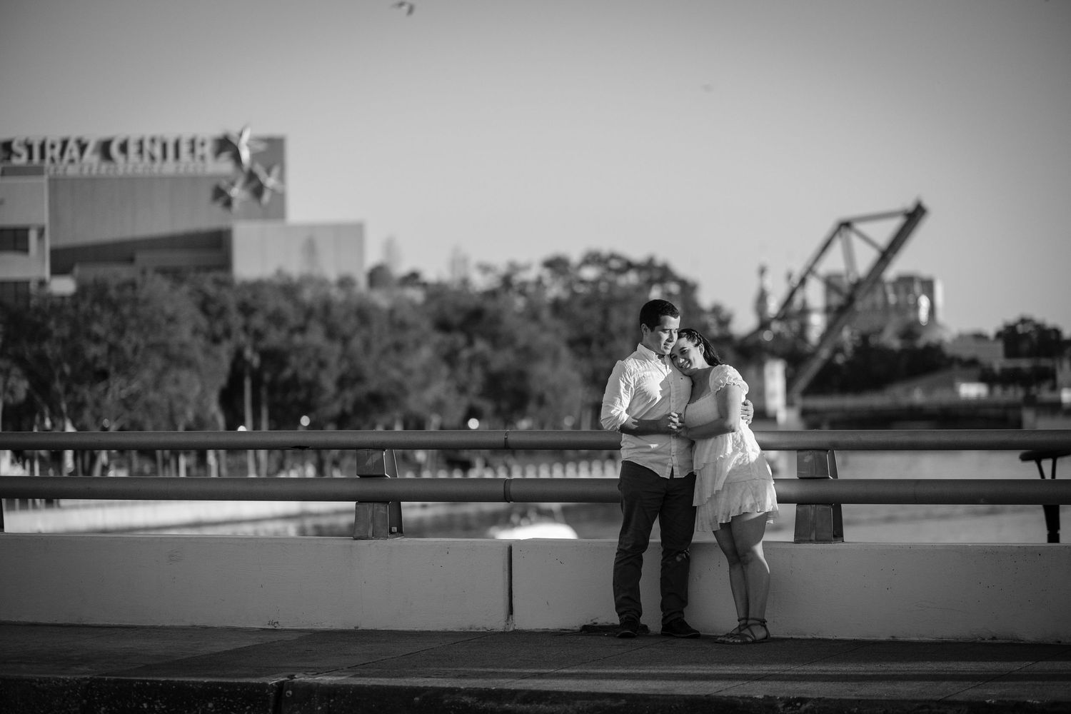 Black and white photo of a couple embracing near the Straz Center waterfront in Tampa, Florida.