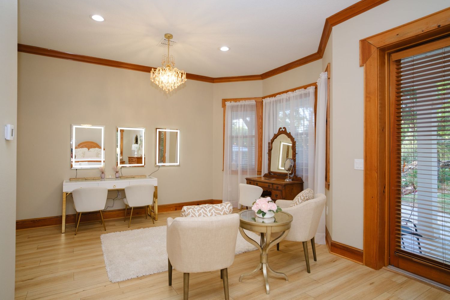 Elegant beauty salon interior with cream chairs, vanity stations, wooden trim and crystal chandelier in natural lighting.