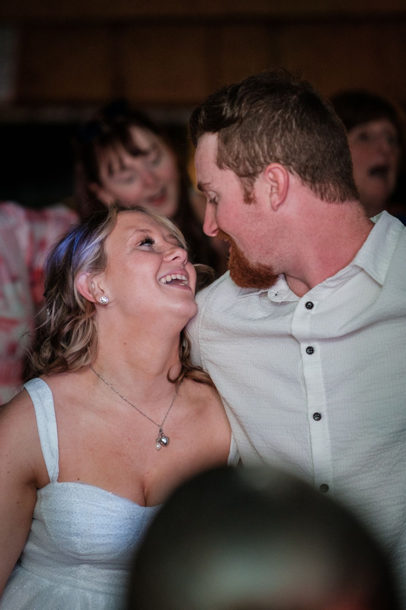 A couple shares a candid laughing moment during what appears to be their wedding celebration.