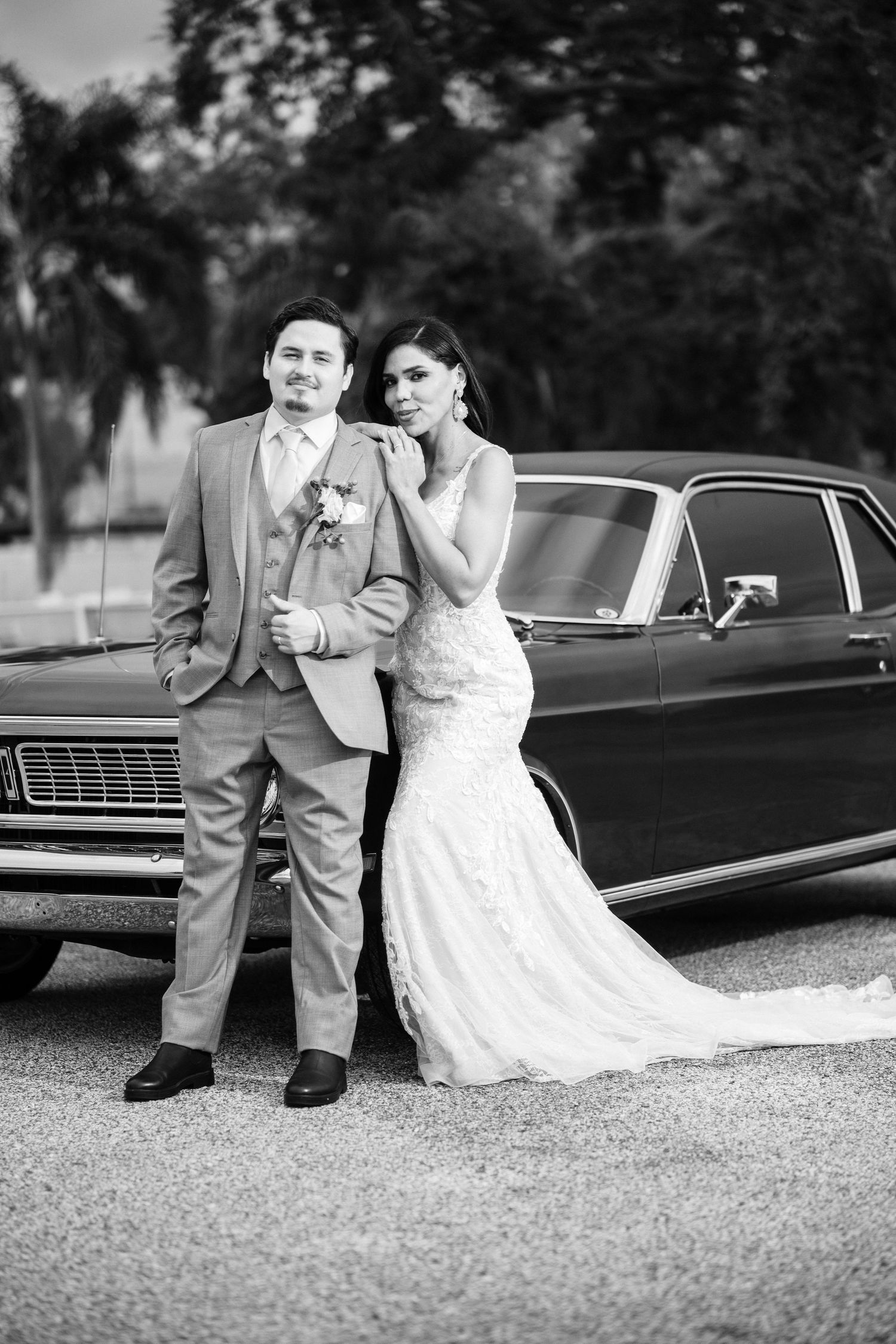 A bride and groom pose together in a series of black and white photos next to a vintage car.