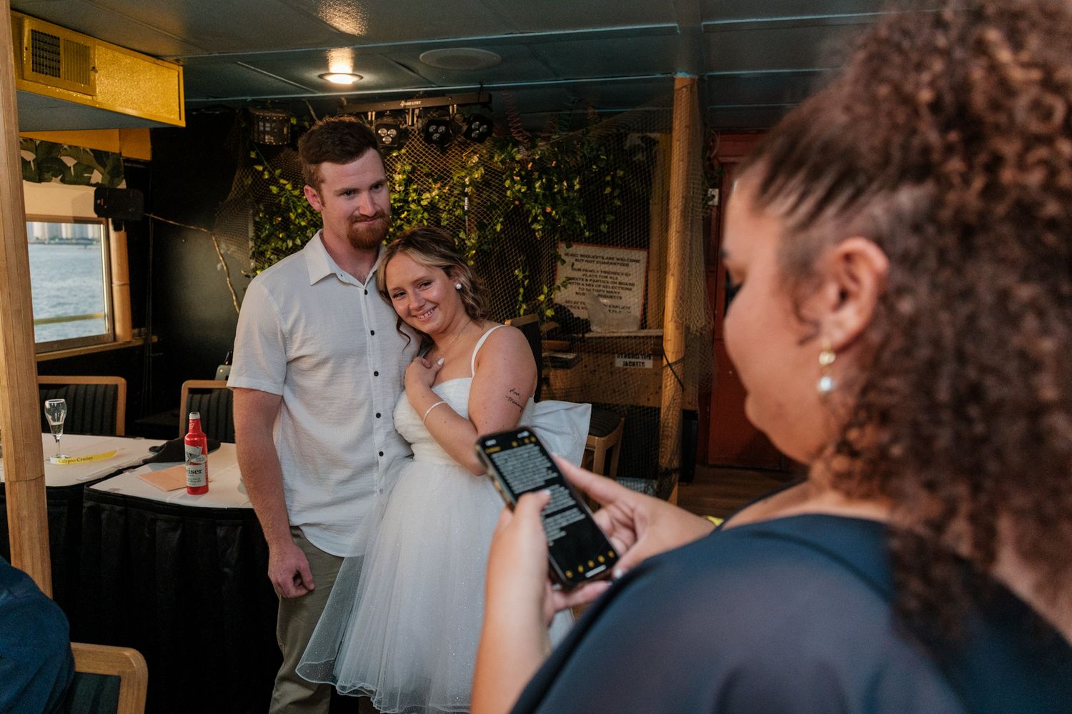 Wedding guests gather in a dimly lit indoor venue during a reception celebration.