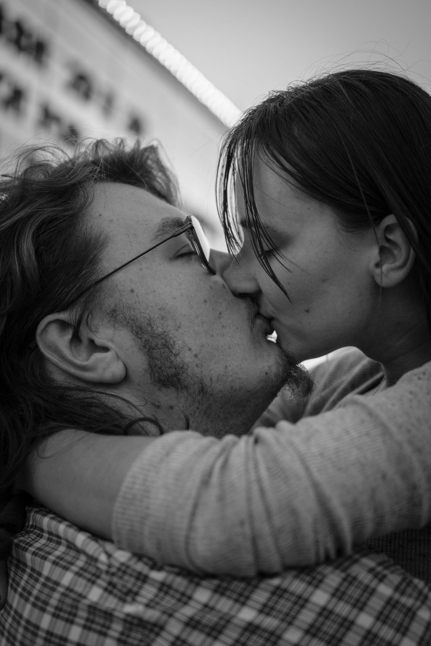 Black and white photo of a couple sharing a romantic kiss while embracing outdoors.