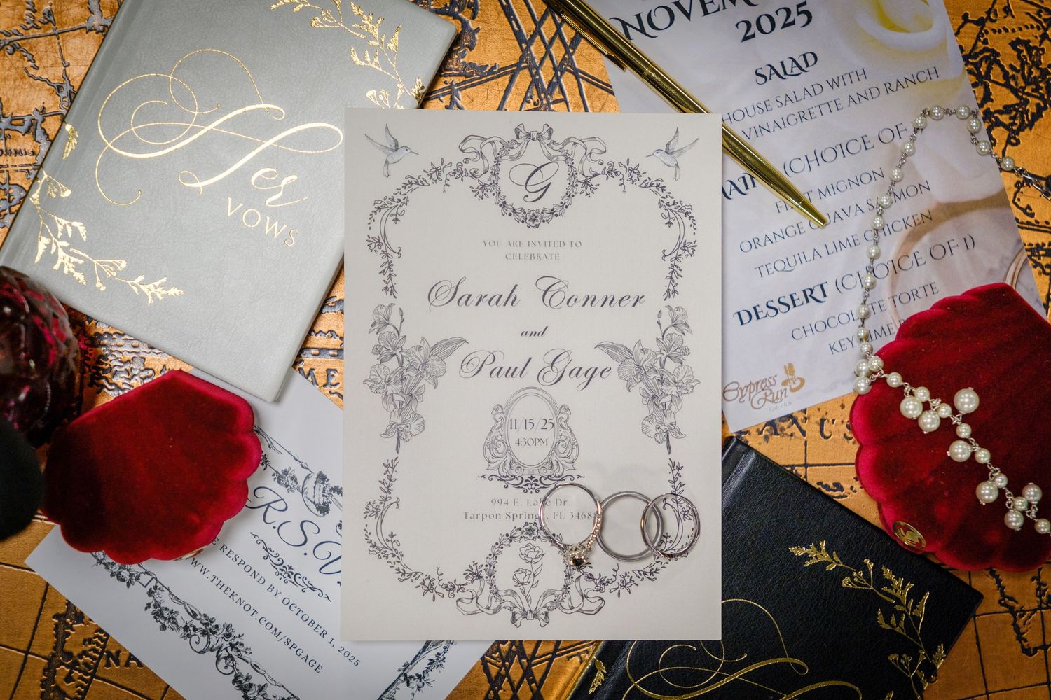 Elegant wedding invitation suite with vintage calligraphy designs and red rose petals on a light background.
