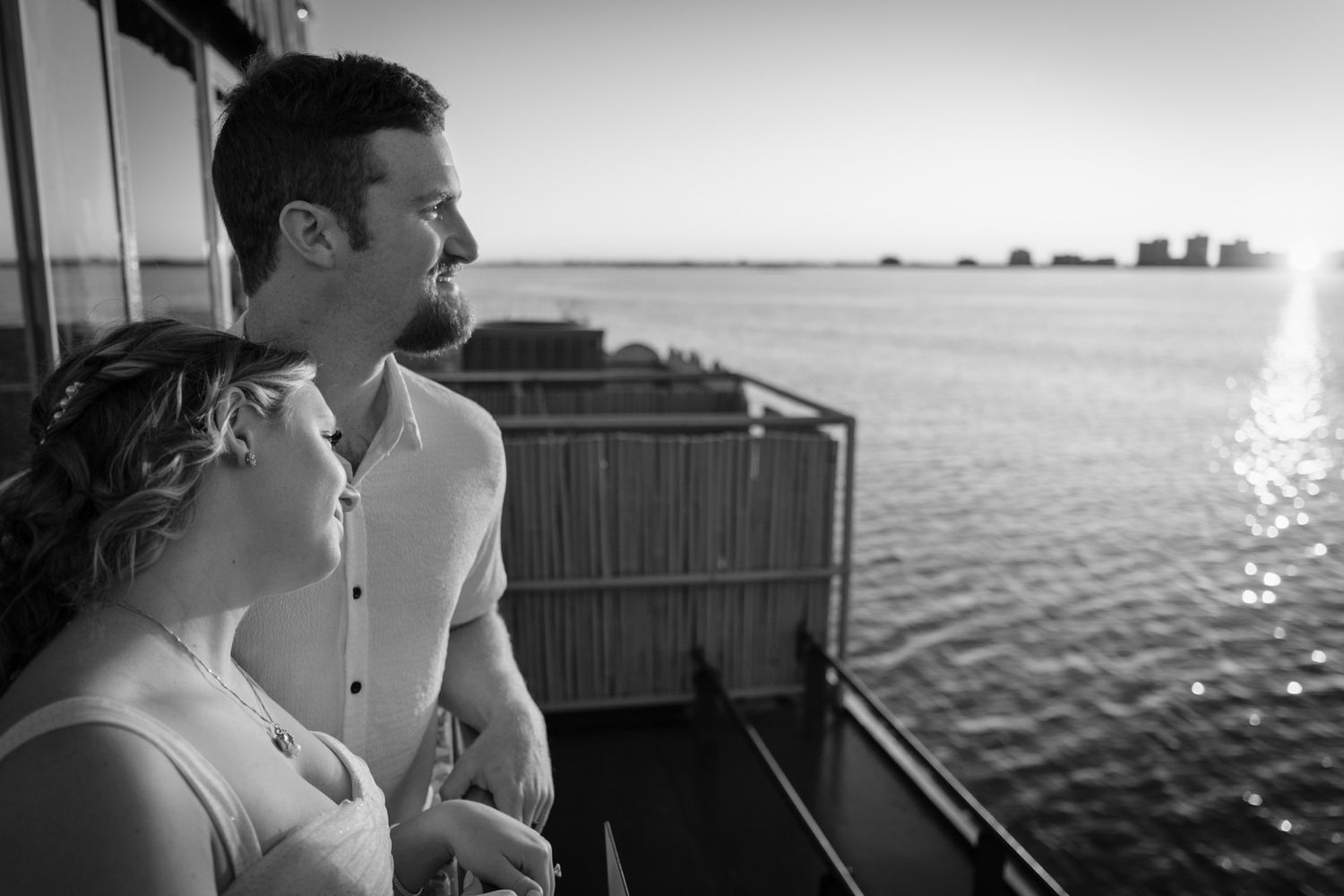 Silhouetted couple enjoying a scenic waterfront view during sunset.