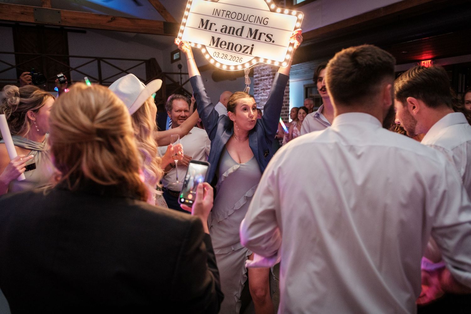 Newlyweds Mr. and Mrs. Menozi celebrated at their wedding reception, surrounded by cheering guests on the dance floor.