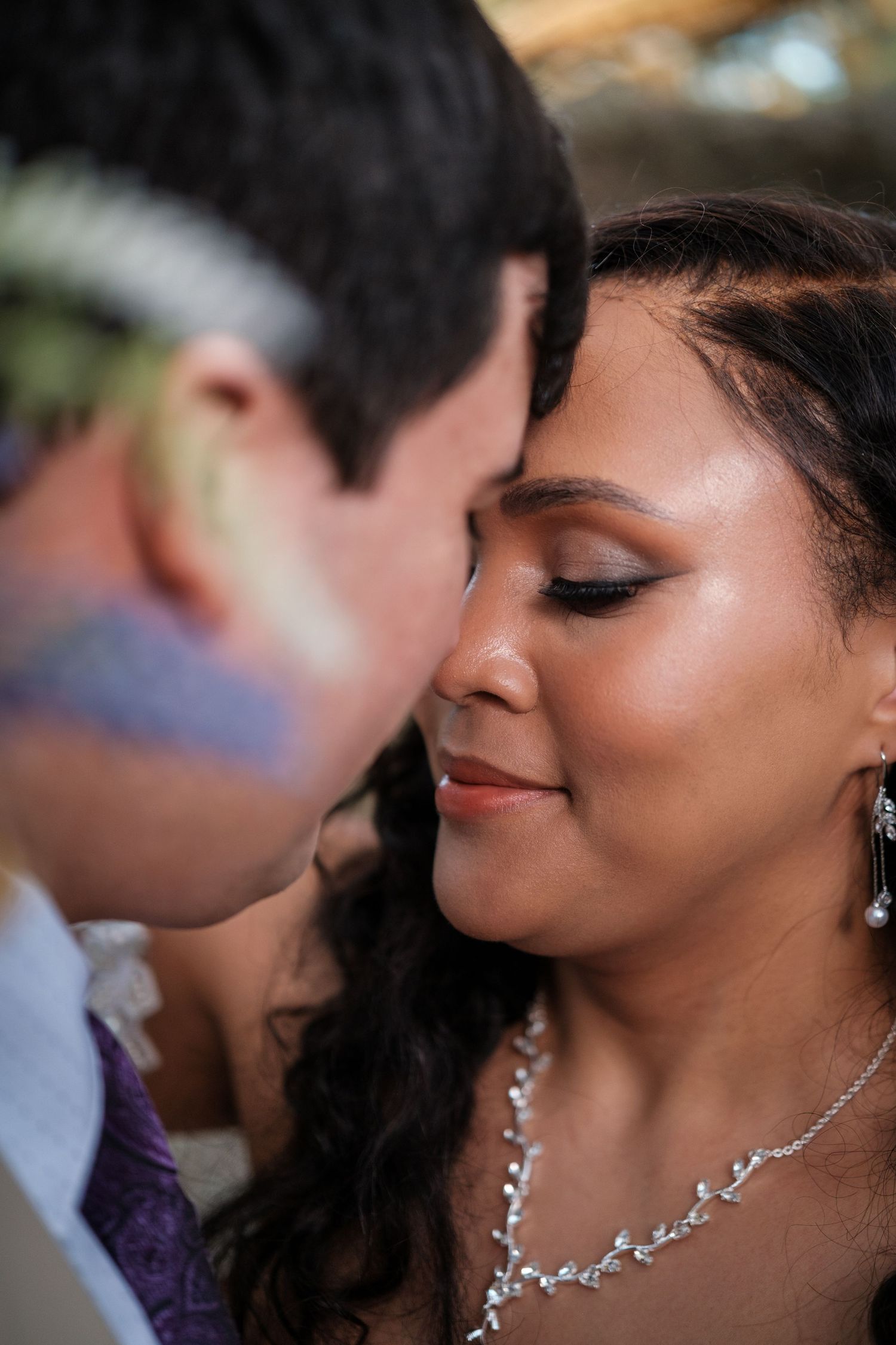 Close-up romantic wedding photo showing couple sharing an intimate moment with elegant jewelry details.