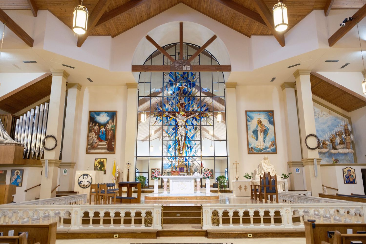 Beautiful Catholic church interior with stained glass cross window above ornate altar.