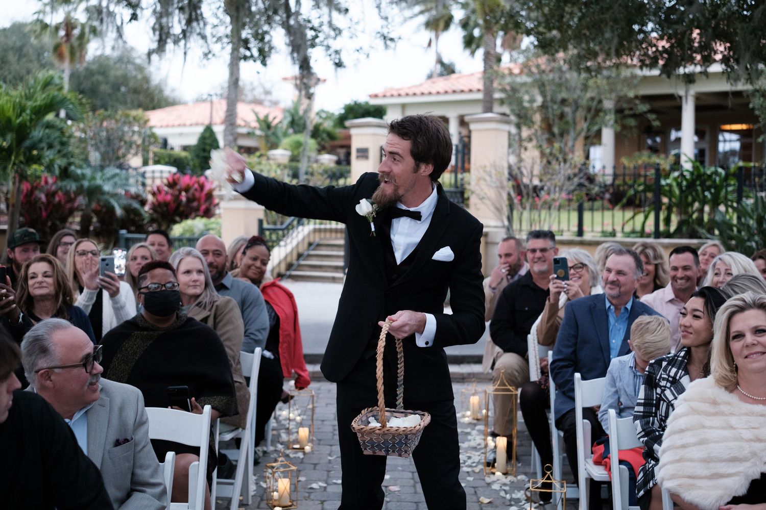 A group of people dancing and celebrating at an outdoor wedding reception under string lights.