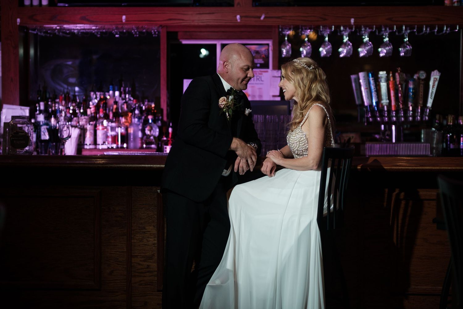 Wedding reception venue with dance floor and bar area illuminated in purple lighting.