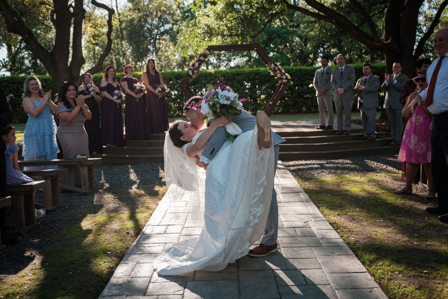 A groom dips his bride for a kiss at the end of the wedding ceremony aisle.