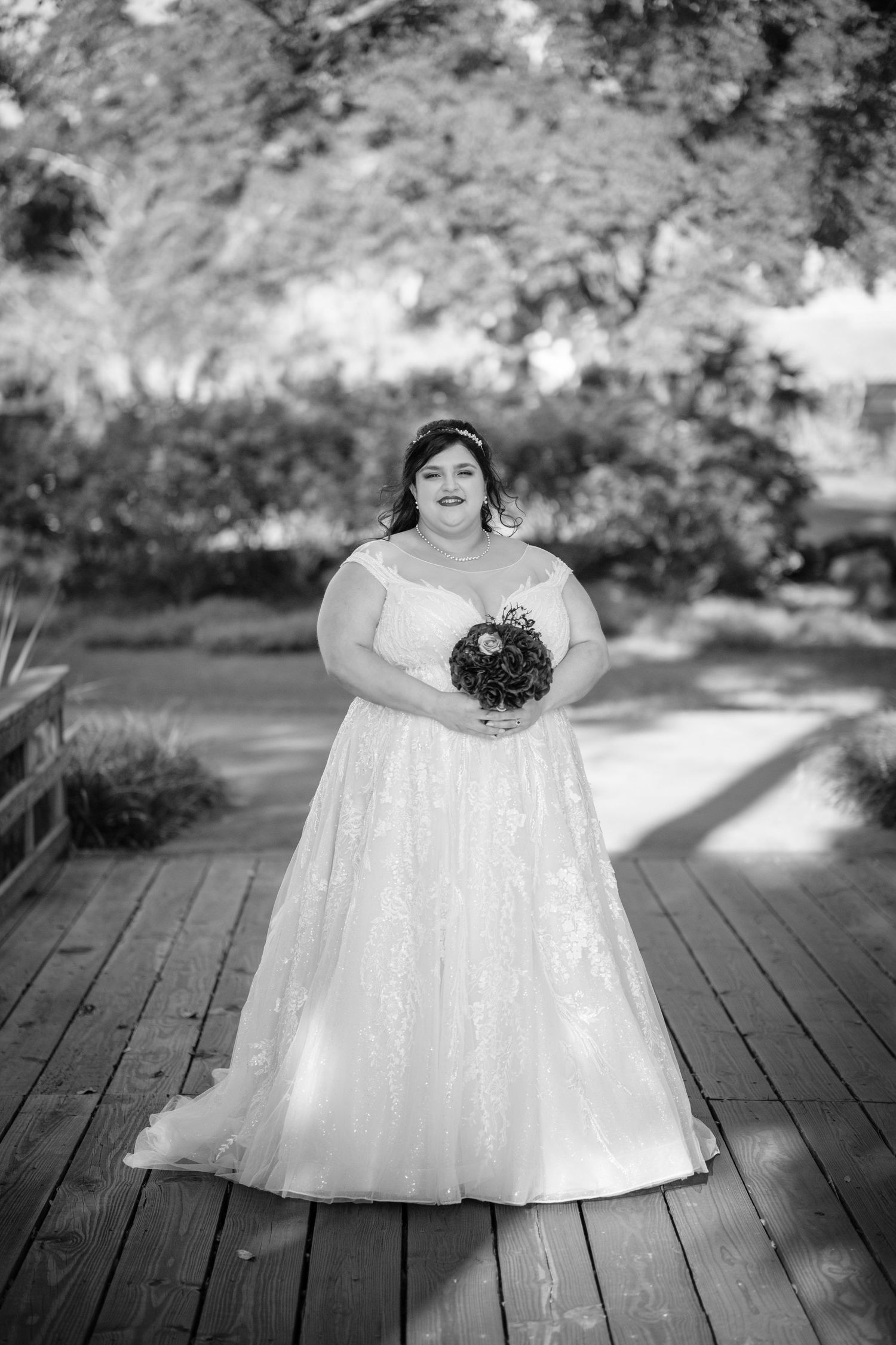 A black and white photo series showing a child in a white dress sitting and posing on a wooden deck outdoors.
