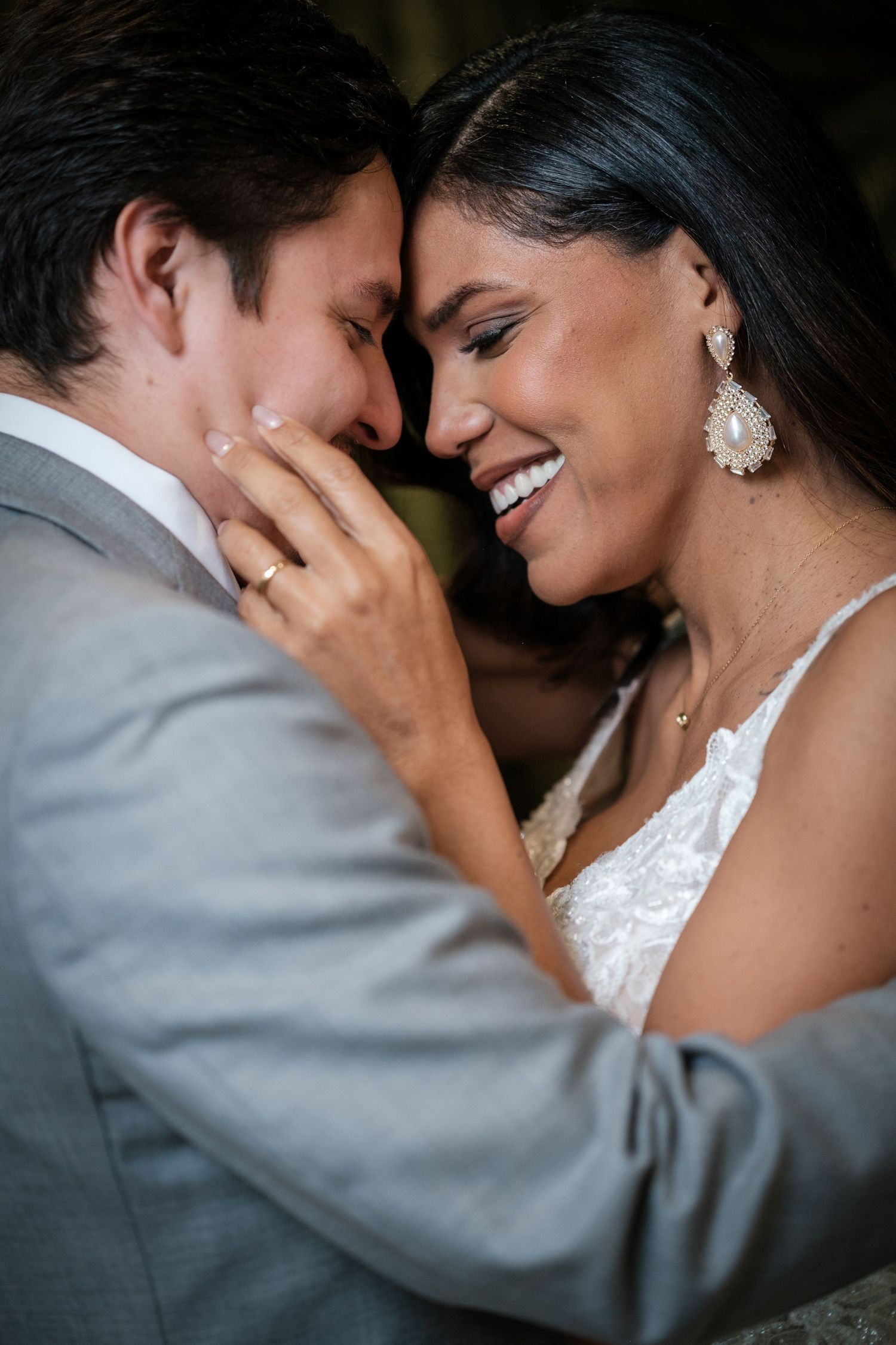 A tender moment between newlyweds as they share an intimate embrace, with the bride wearing elegant earrings and lace.