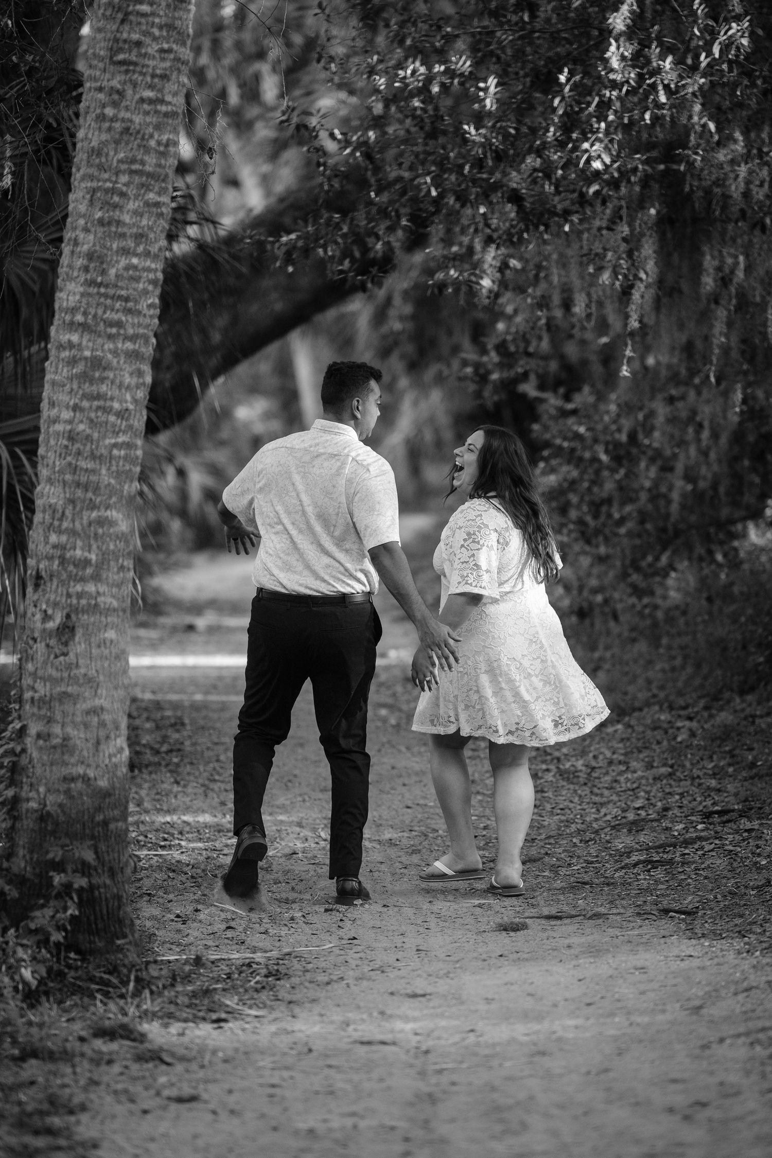 A couple walking down a path in Philippe Park during their engagement photo session