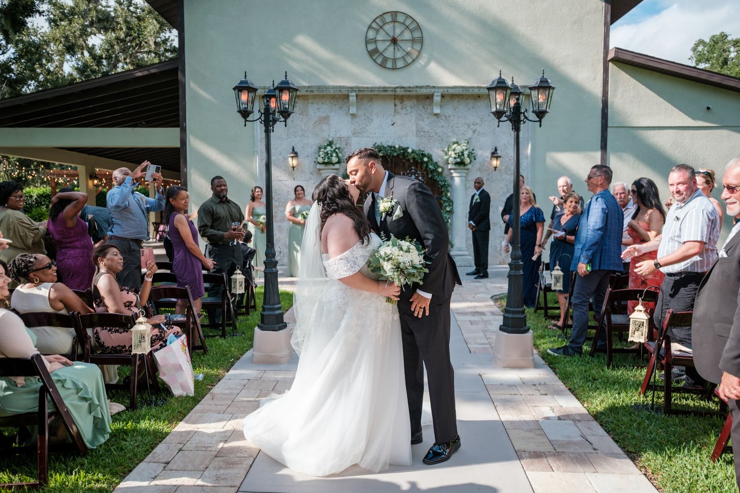 Wedding ceremony taking place in an elegant outdoor pavilion with white columns and decorative lanterns.