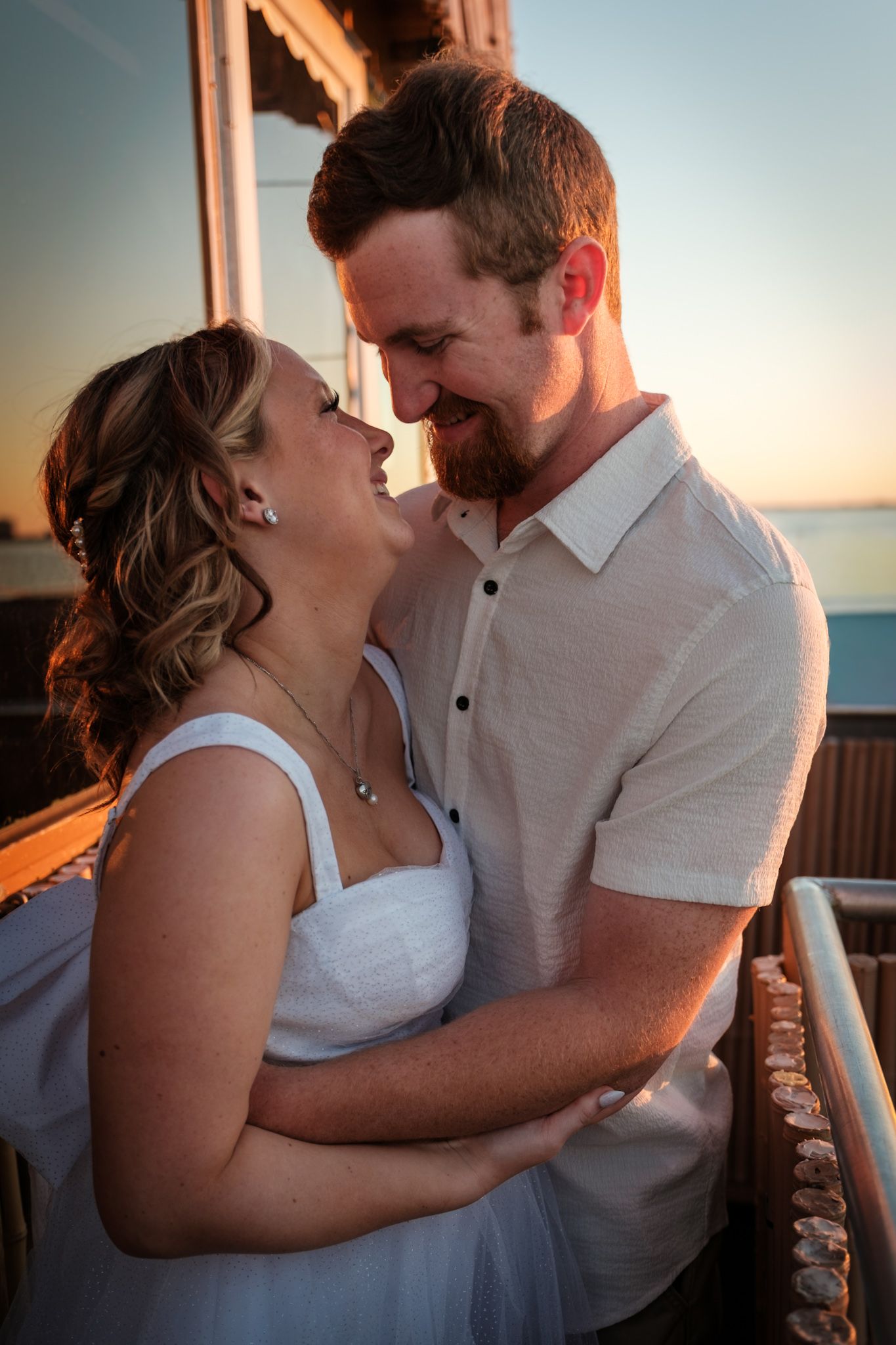 A romantic couple shares an intimate moment at sunset on a boat deck.