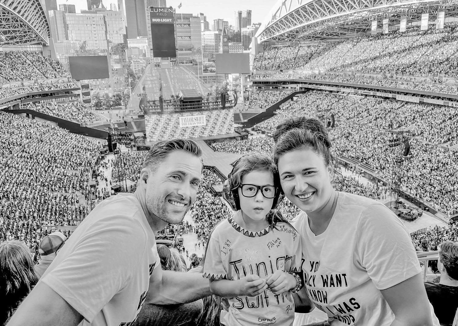 Candid stadium shot showing three people at a crowded sports event or concert.