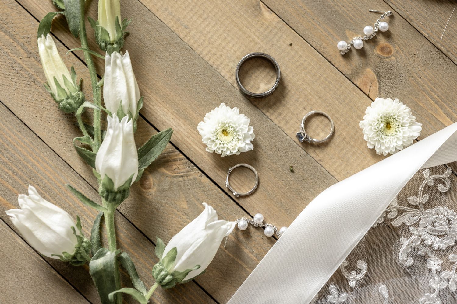 Green lisianthus flower buds and white blooms arranged with scattered small white flowers on a rustic wooden surface.