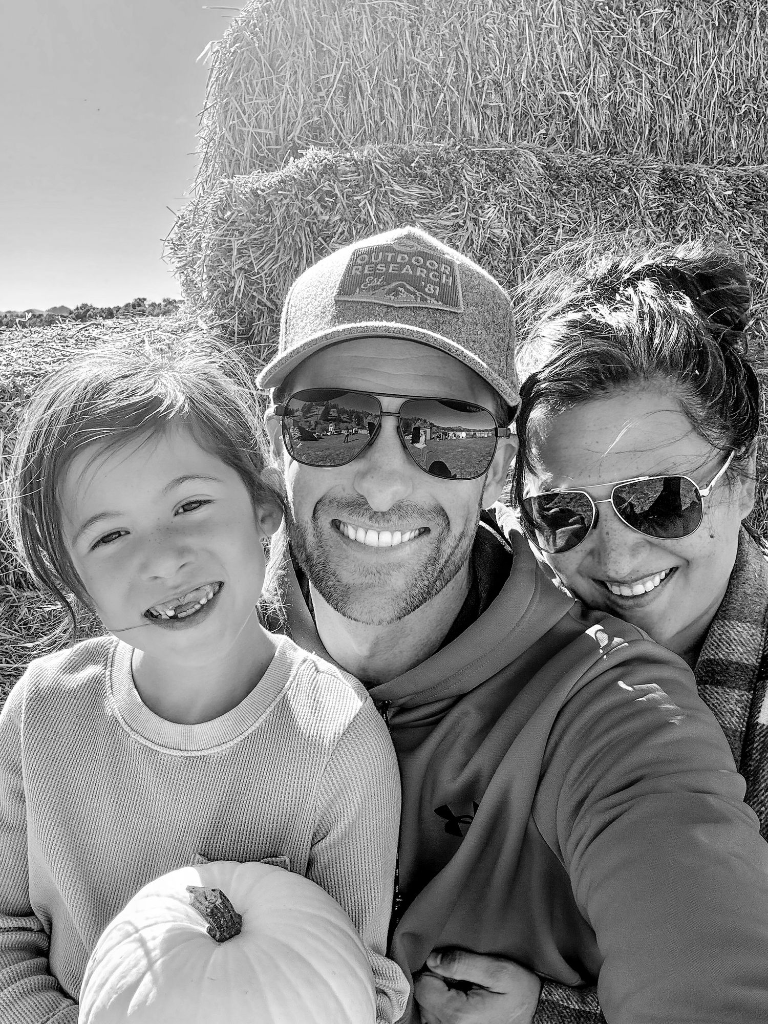 Fall family selfie with pumpkin and hay bales in the background.