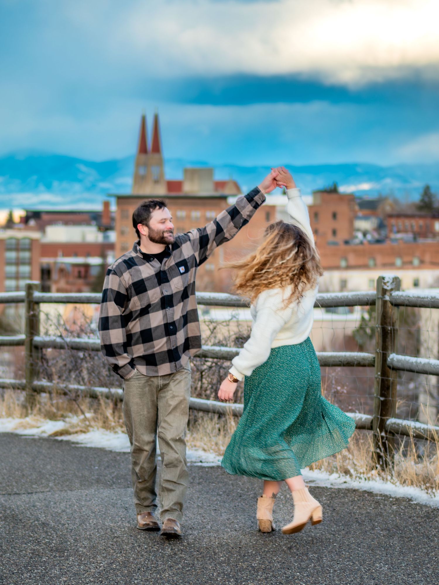Couple dancing together on pathway with city skyline in background.
