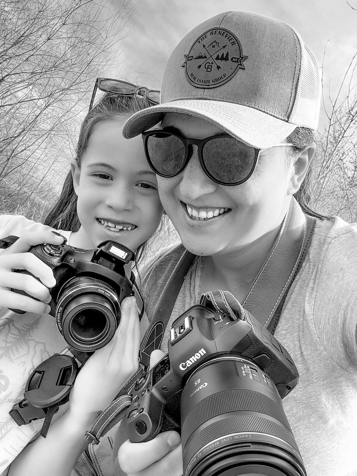 Two photographers holding cameras and smiling together outdoors.