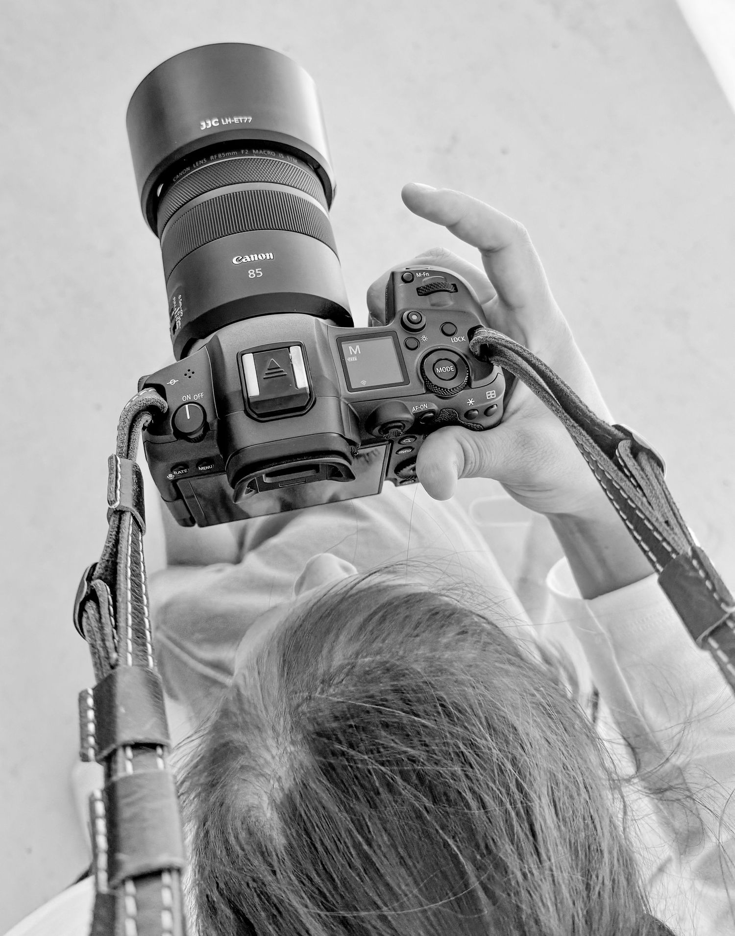 Close-up overhead view of hands holding a professional camera with a telephoto lens.