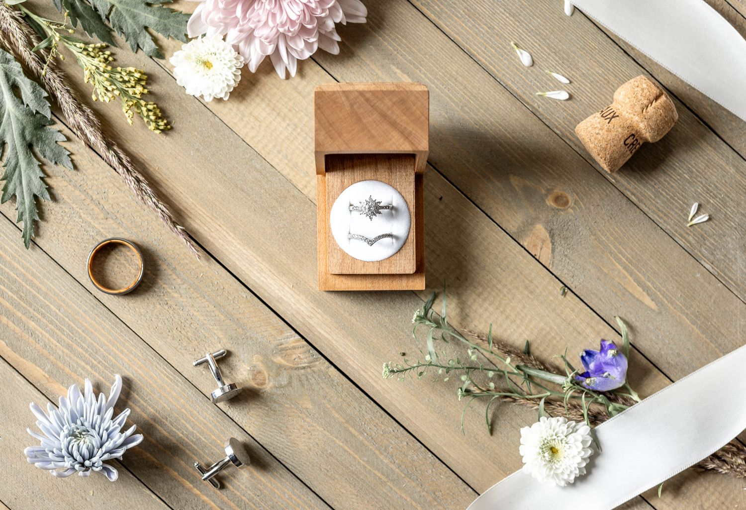 Various paper items and craft supplies arranged on a rustic wooden table with dried floral accents.