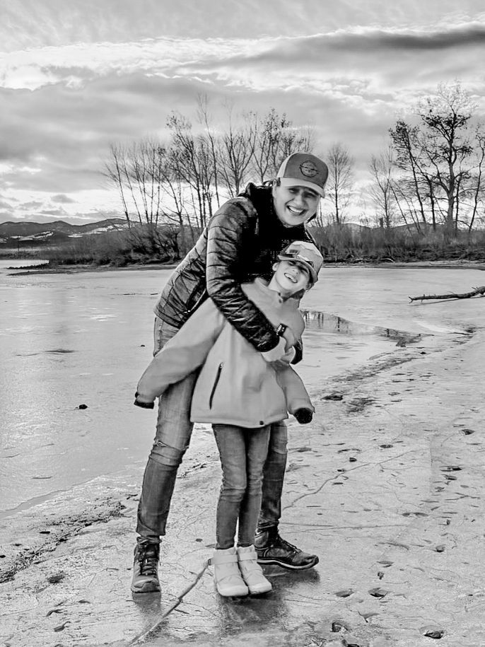 Two people playing and having fun on a winter beach with mountains in the background.