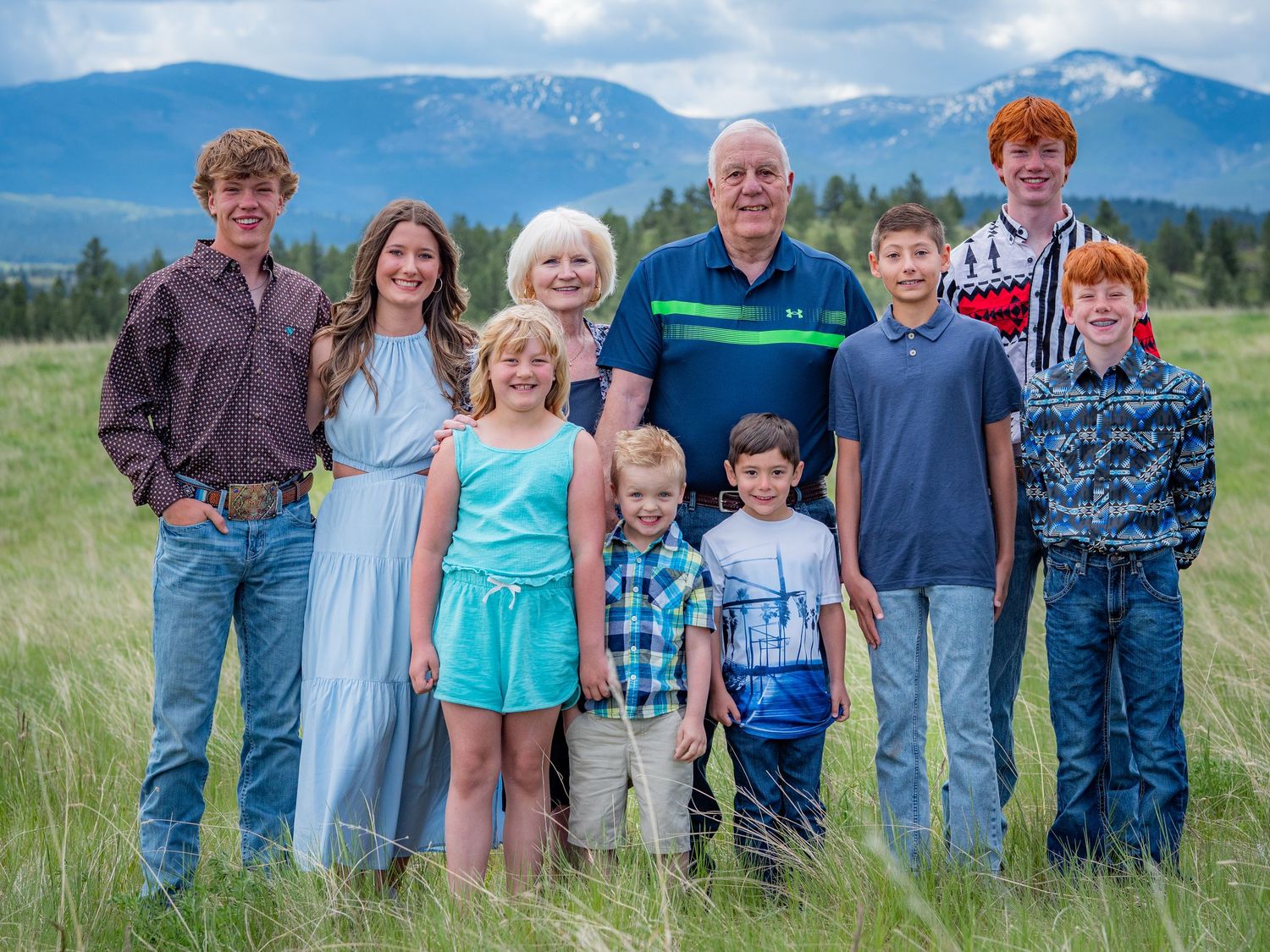 Multi-generational family group portrait with mountain landscape in background.