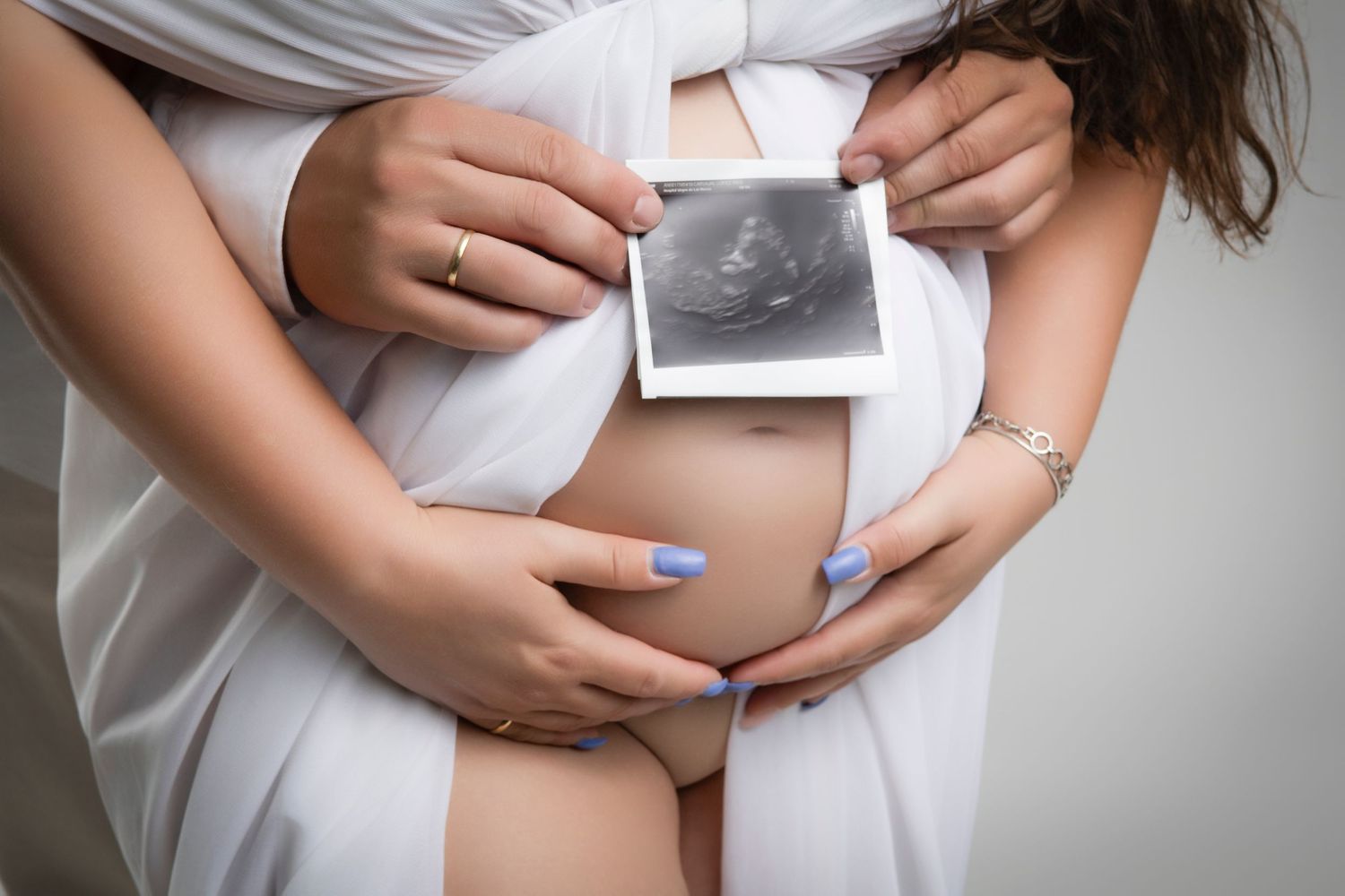 Sesión de fotografía de embarazo en Granada, mamá sosteniendo su barriguita en el estudio