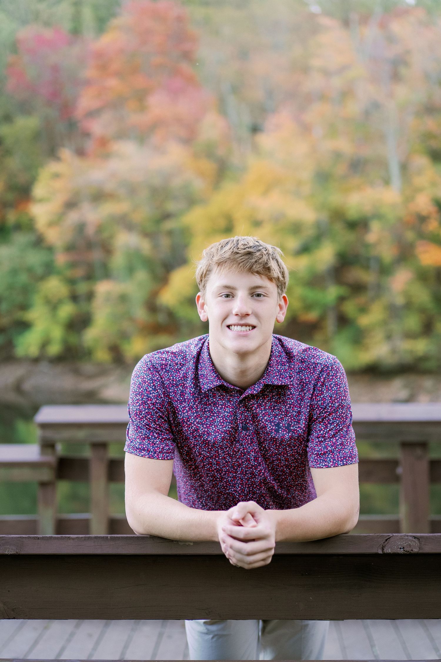 Outdoor autumn portrait featuring purple patterned shirt against colorful fall foliage backdrop.