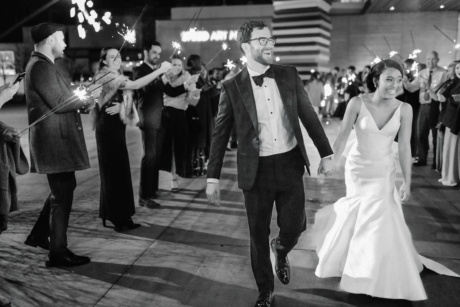 Wedding couple celebrates during their reception dance with guests cheering in the background.