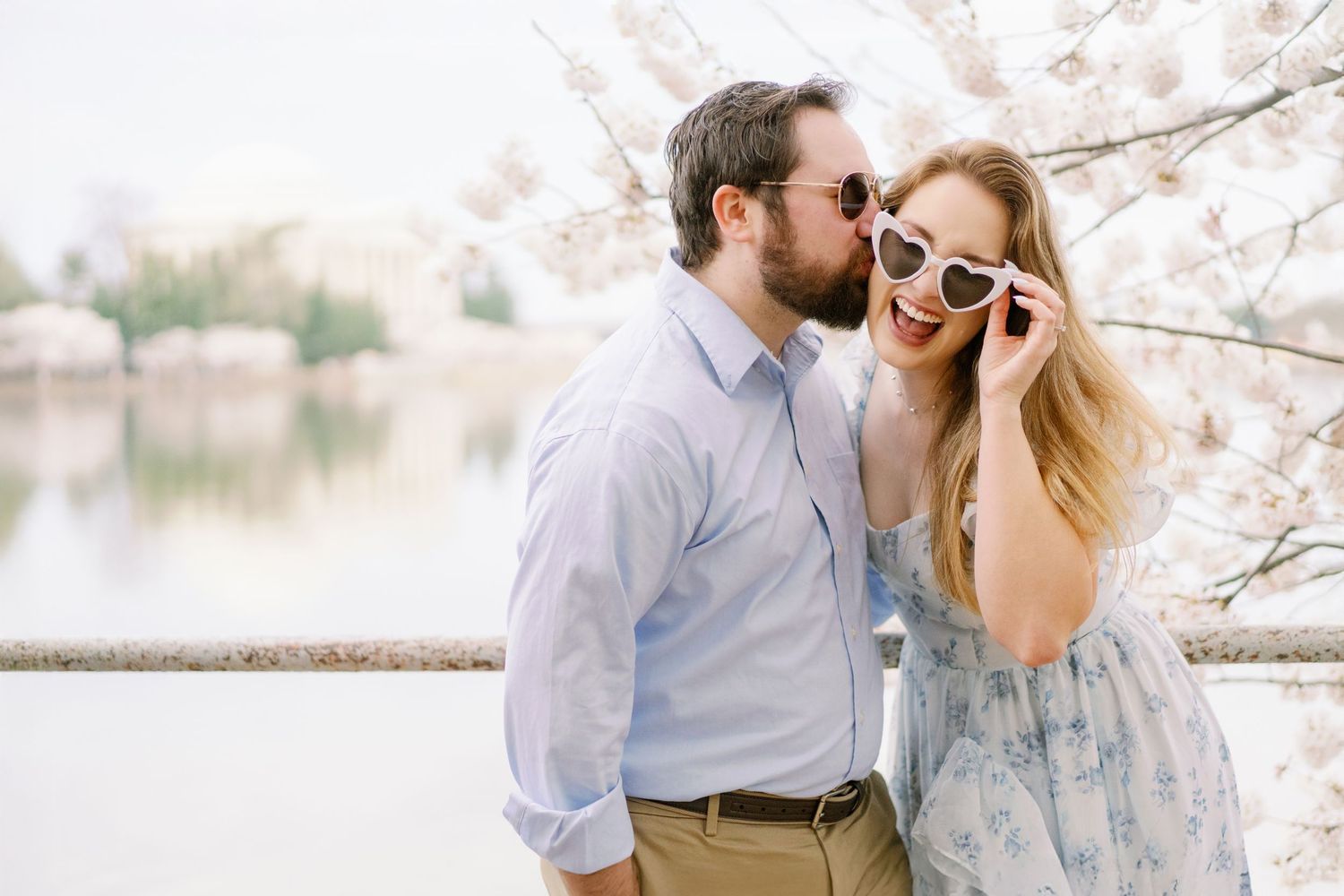 A playful moment among cherry blossoms with the Tidal Basin creating a dreamy backdrop.