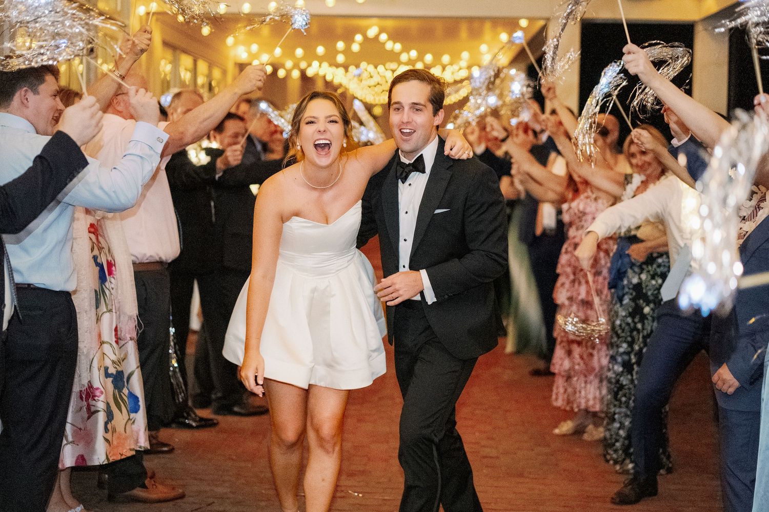 A couple in formal attire dancing at a wedding reception surrounded by guests cheering them on.